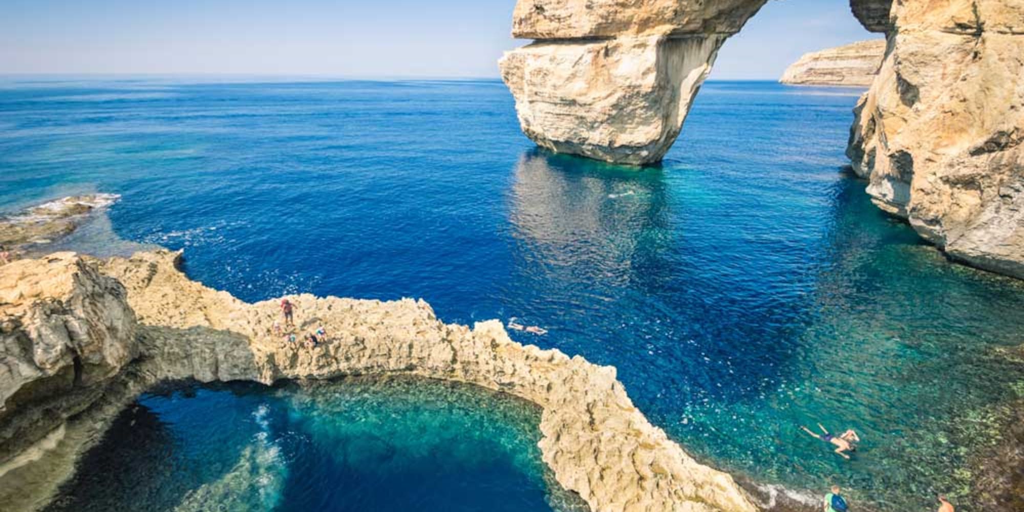 Azure Window natural arch, Gozo, Malta. Swimmers in clear blue water.