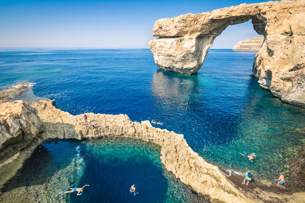 Azure Window natural arch, Gozo, Malta. Swimmers in clear blue water.