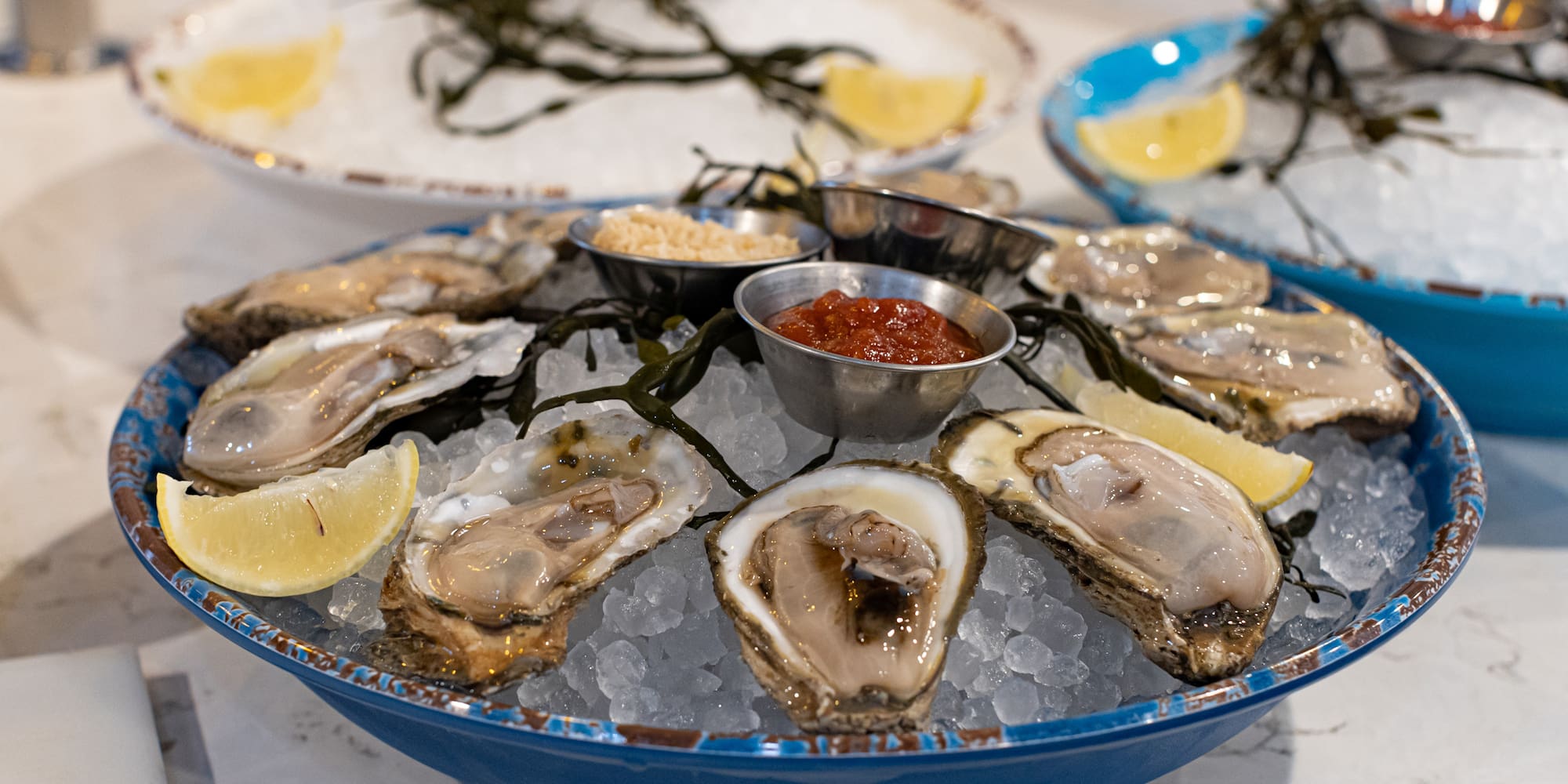 a plate of oysters on ice with lemons and sauces