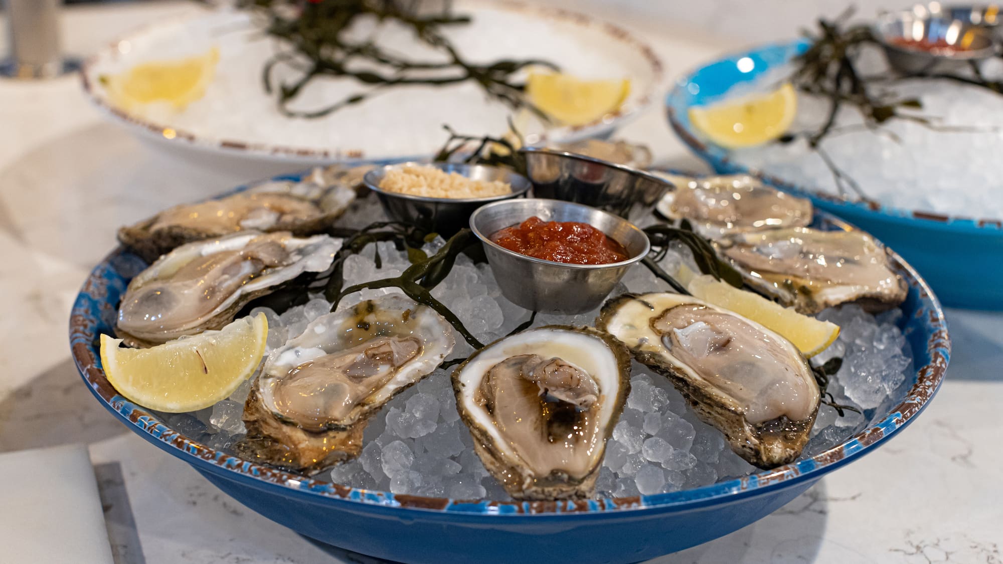 a plate of oysters on ice with lemons and sauces