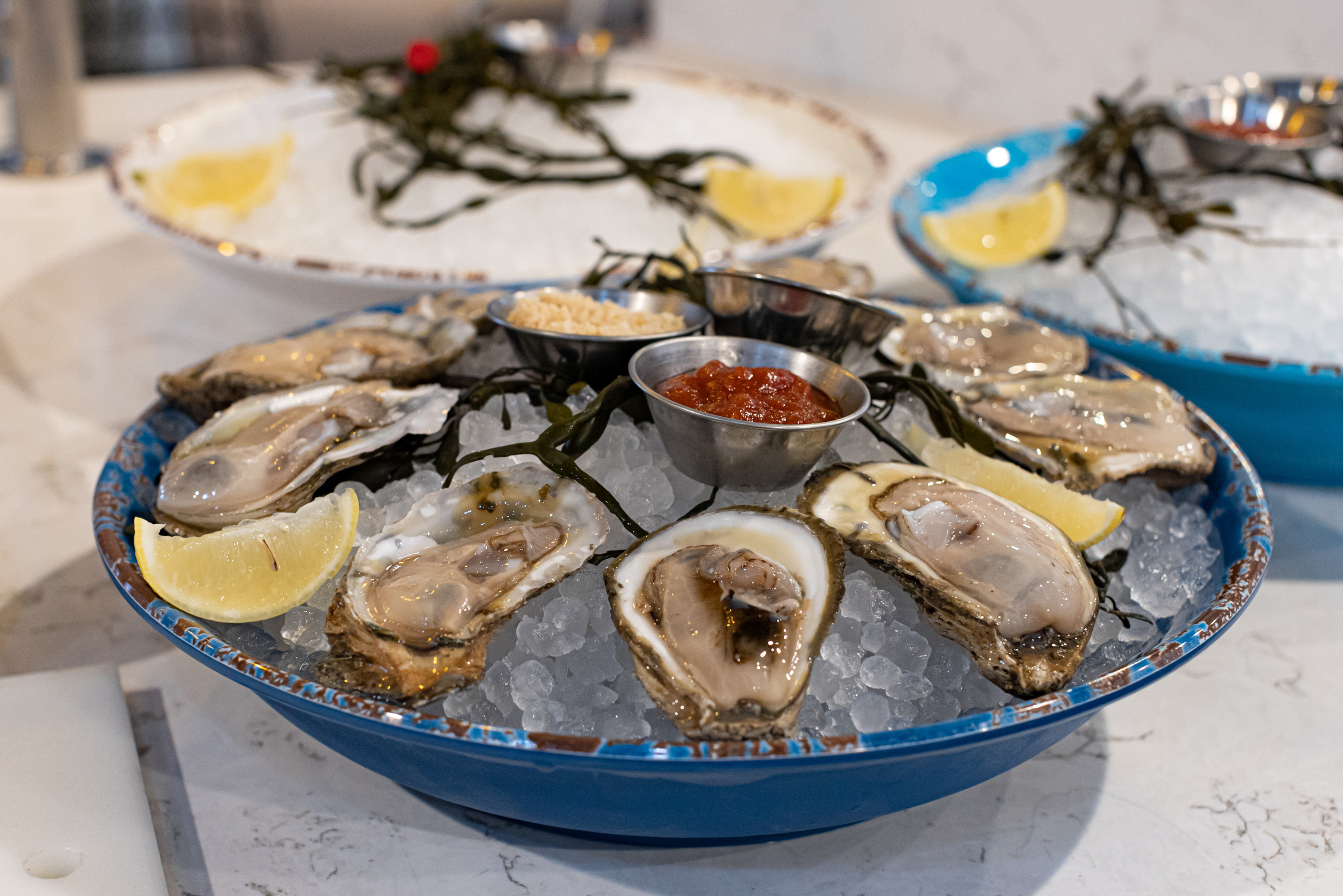 a plate of oysters on ice with lemons and sauces