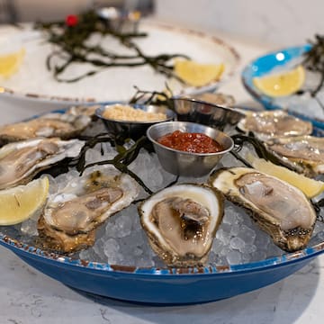 a plate of oysters on ice with lemons and sauces