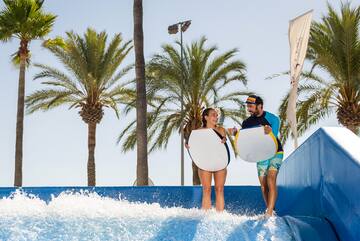 a man and woman holding surfboards on a water slide
