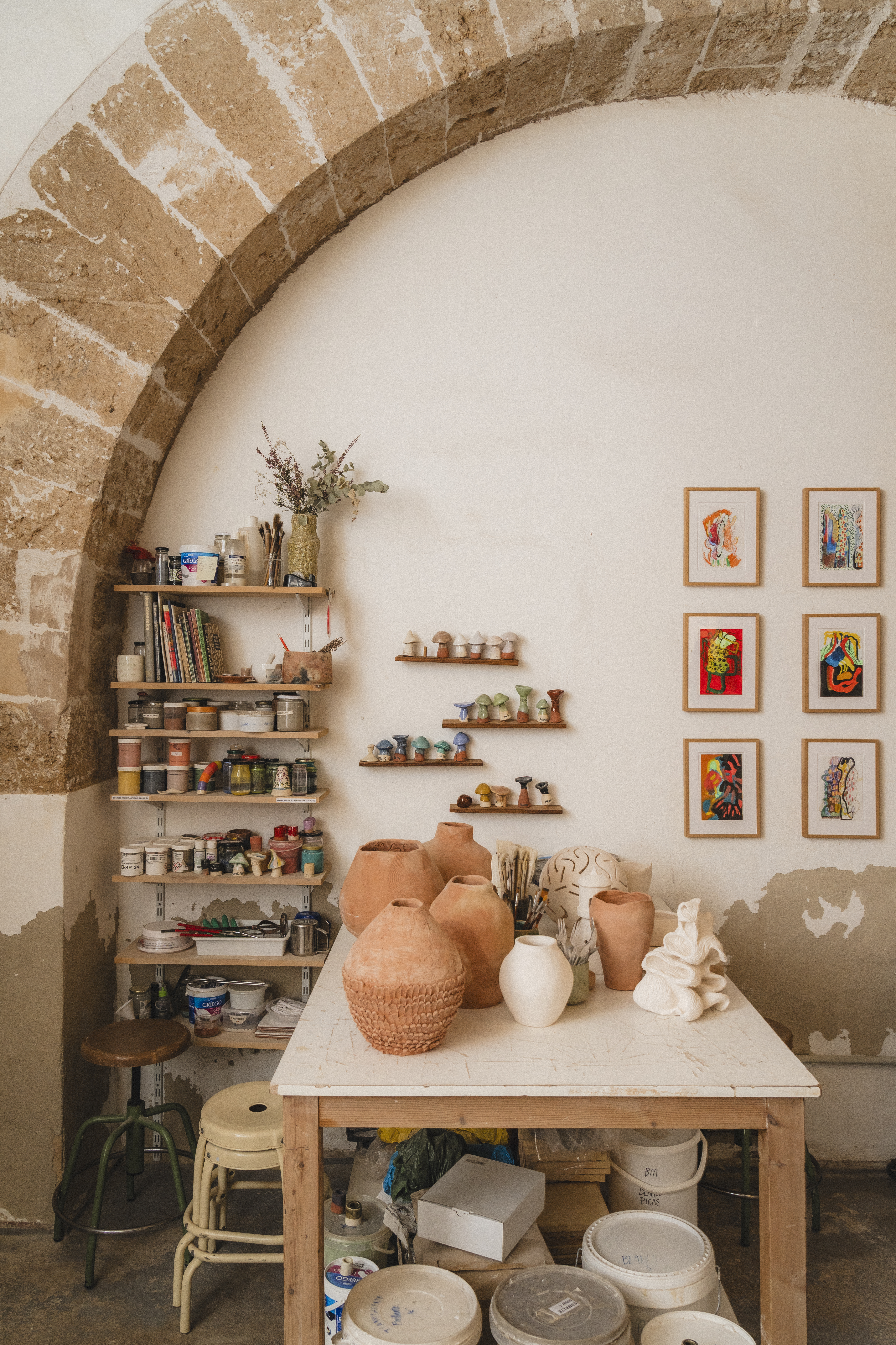 a table with pottery on it and shelves with art on the wall