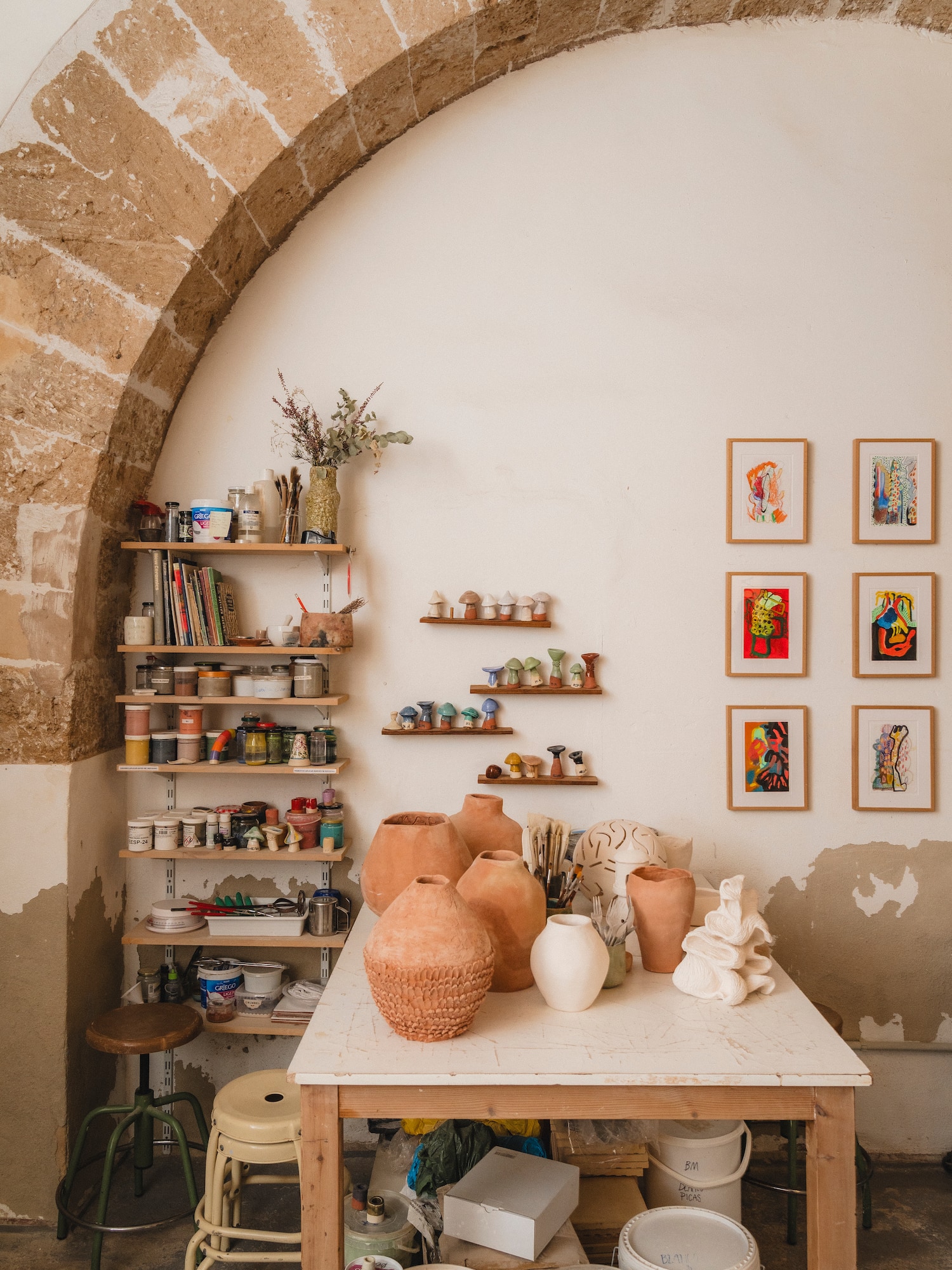 a table with pottery on it and shelves with art on the wall
