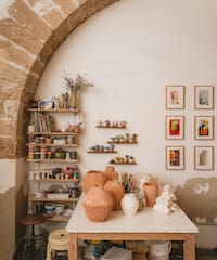 a table with pottery on it and shelves with art on the wall