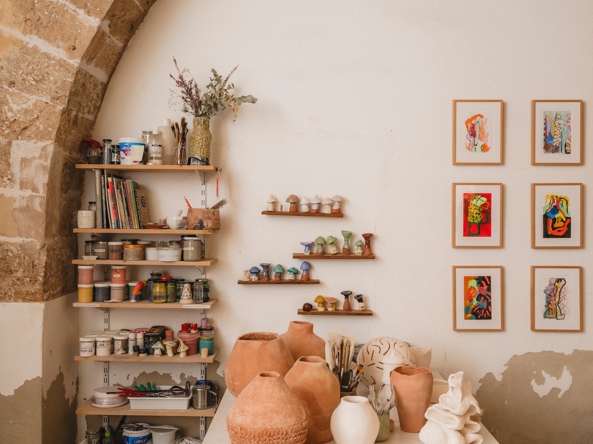 a table with pottery on it and shelves with art on the wall
