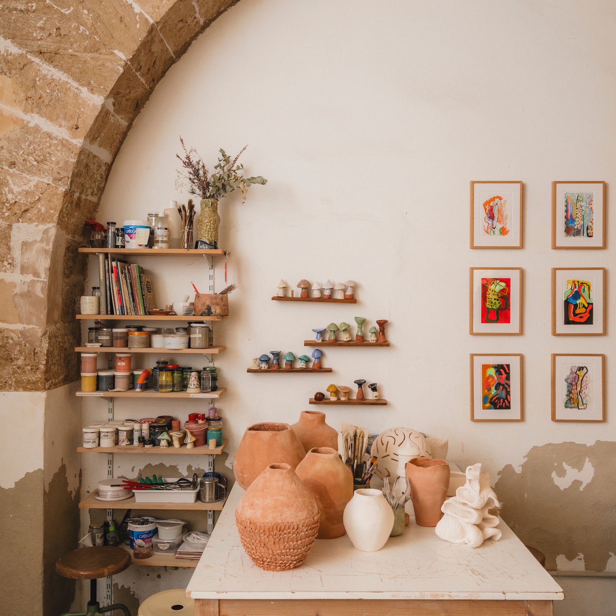 a table with pottery on it and shelves with art on the wall