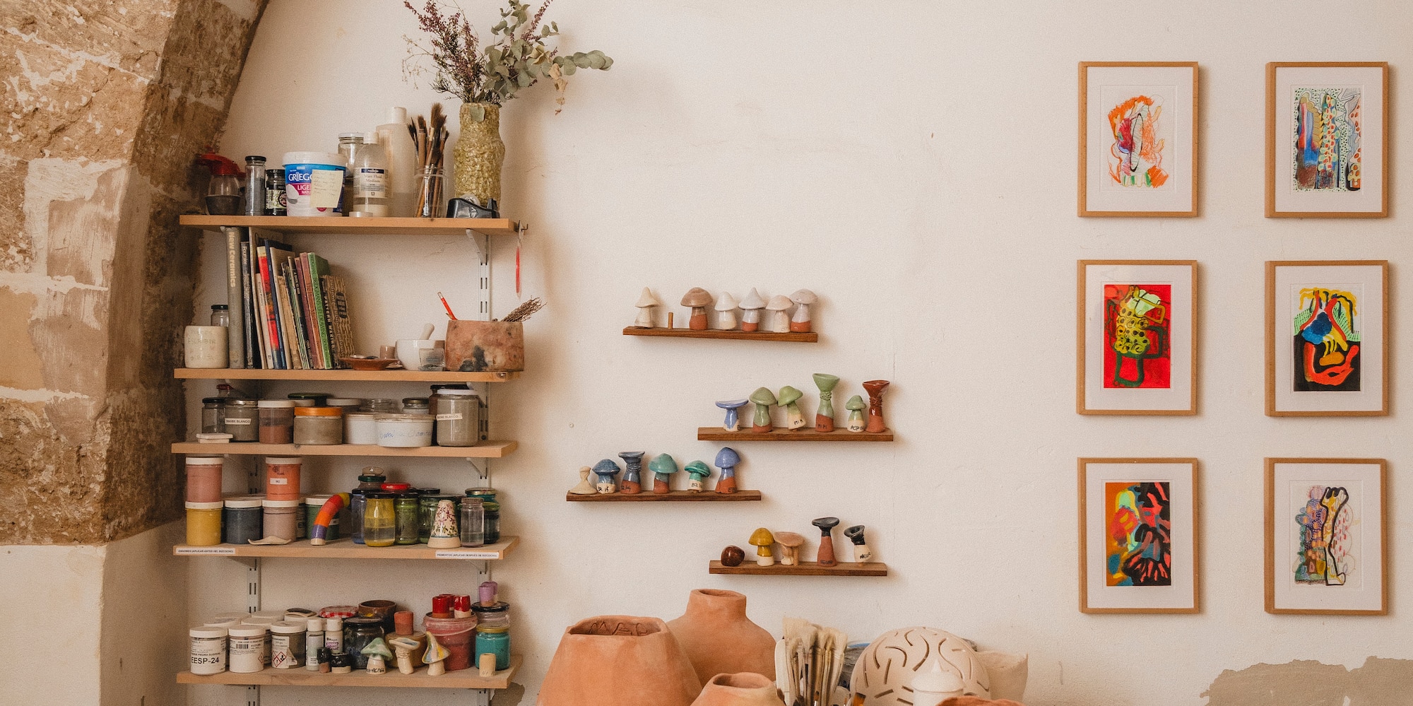 a table with pottery on it and shelves with art on the wall