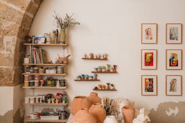 a table with pottery on it and shelves with art on the wall