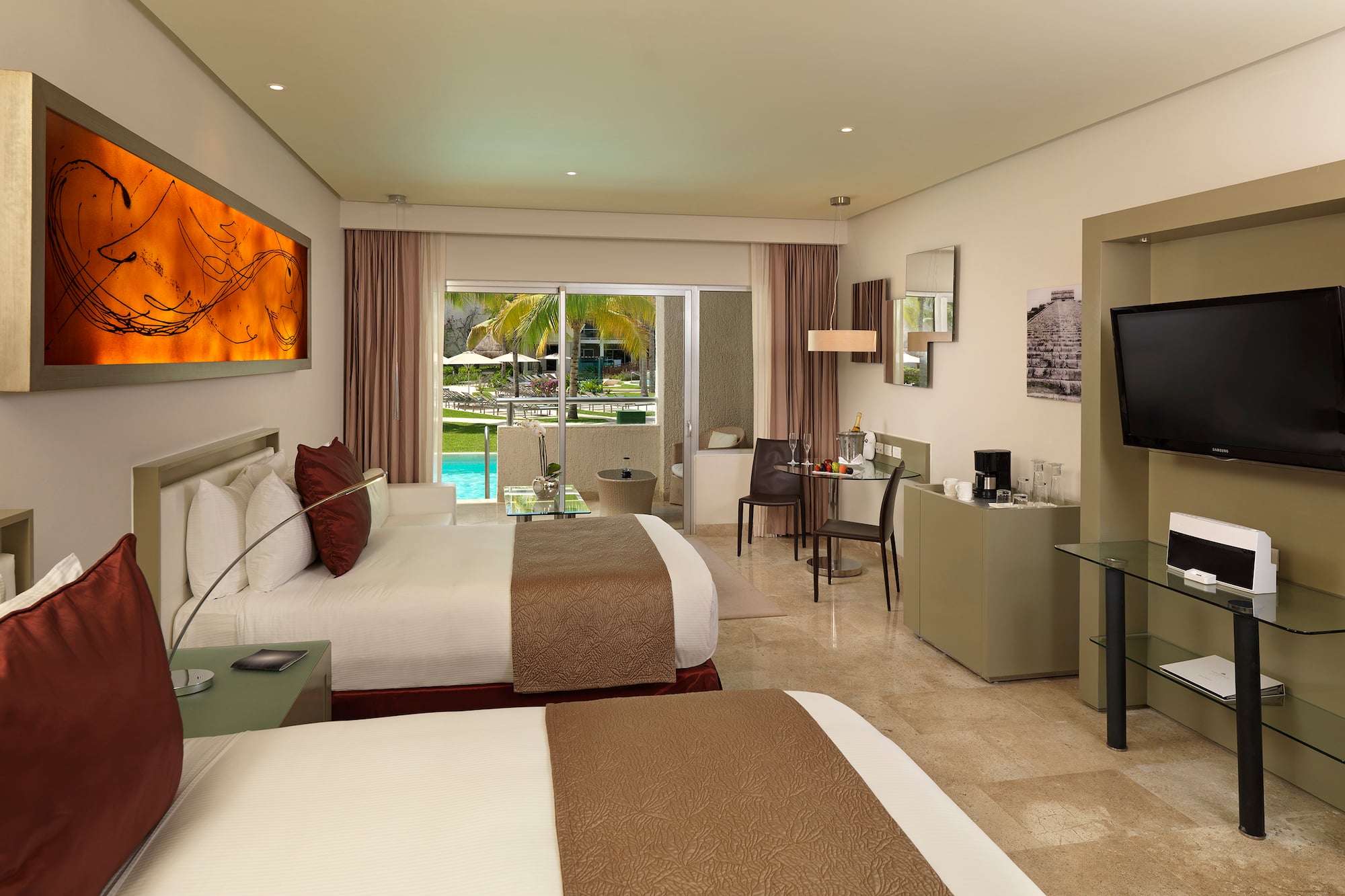 Hotel room with two queen beds, private balcony, and tropical pool view.