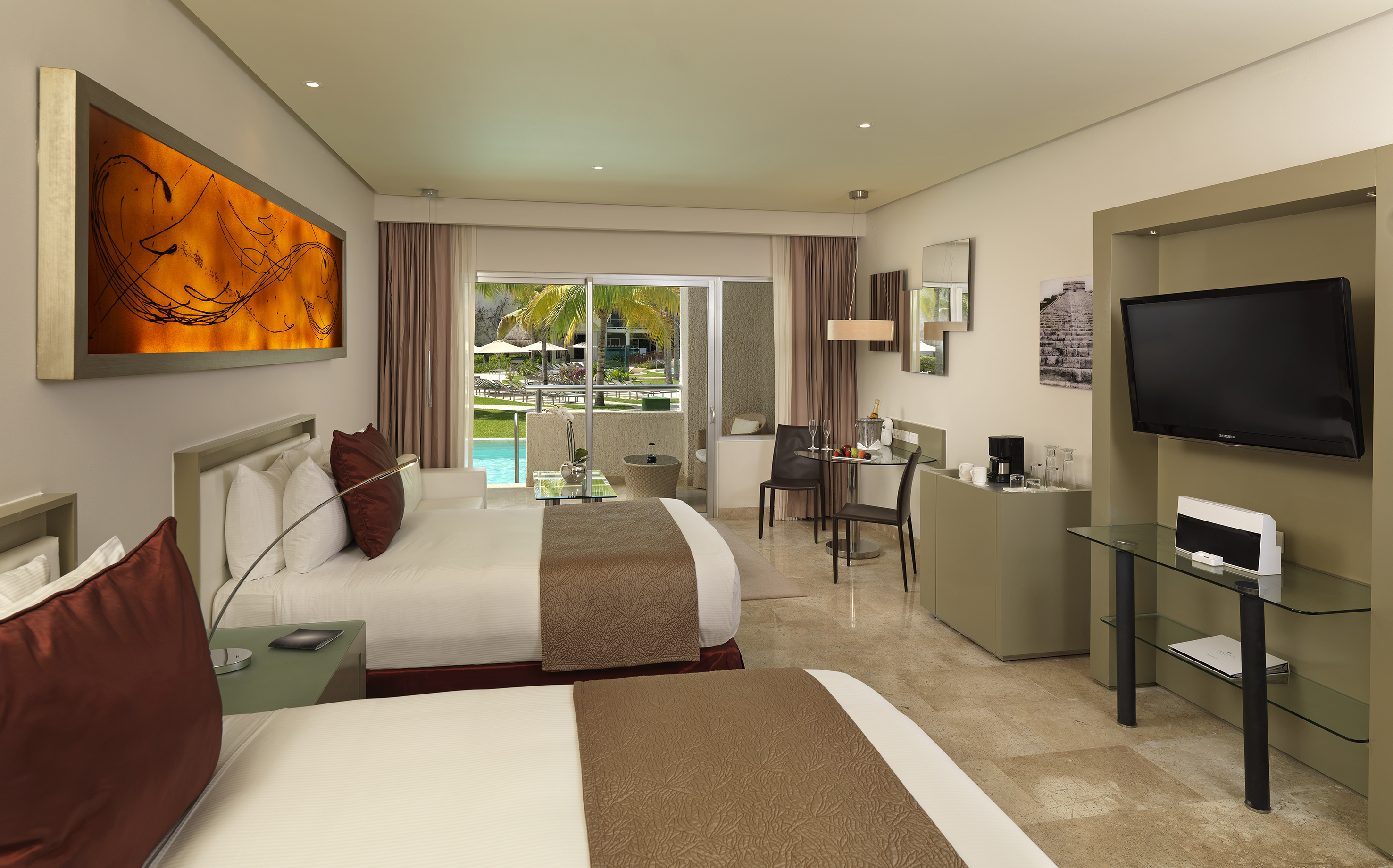 Hotel room with two queen beds, private balcony, and tropical pool view.