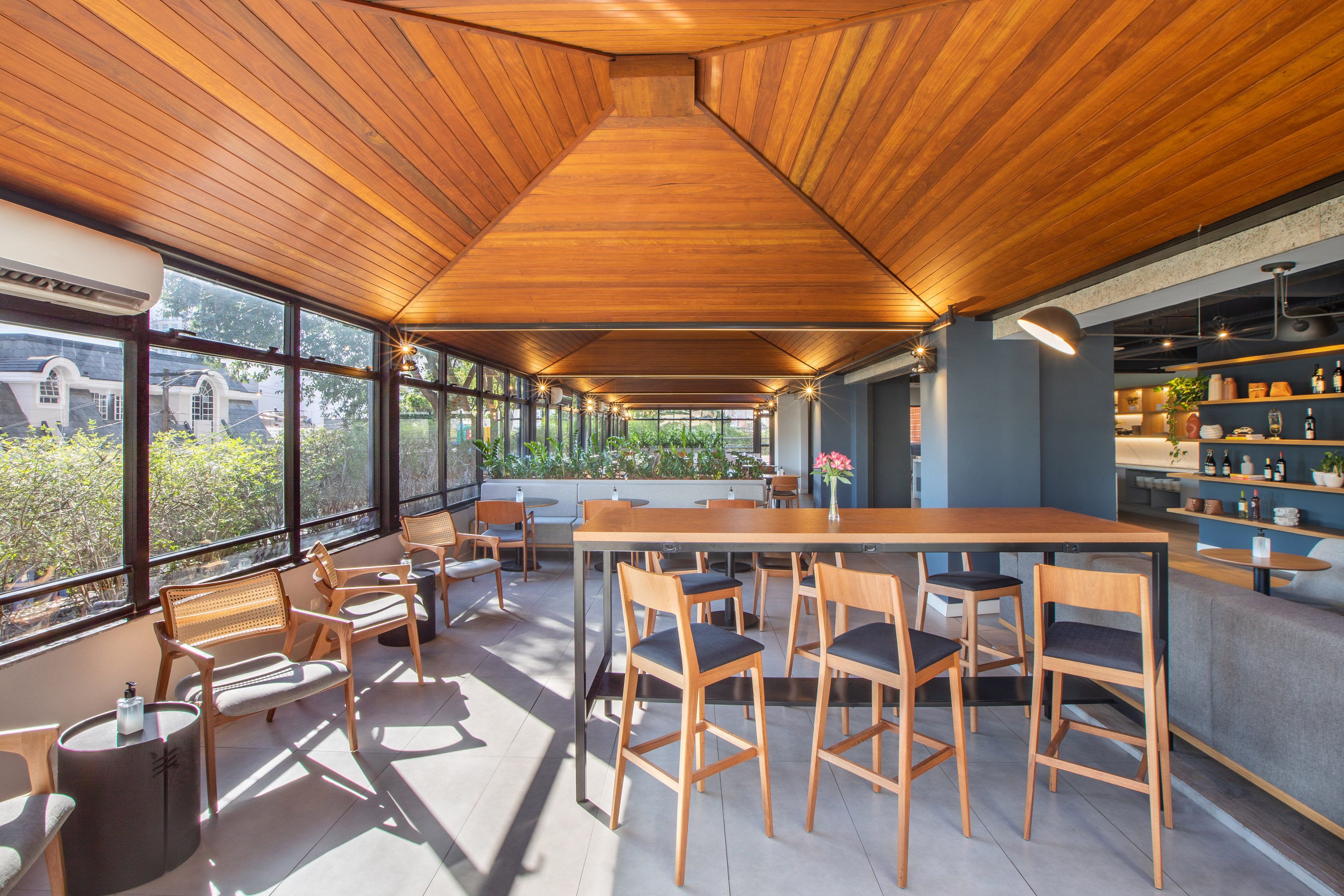 Modern cafe lounge with wooden ceiling, bar table, and bright window views.