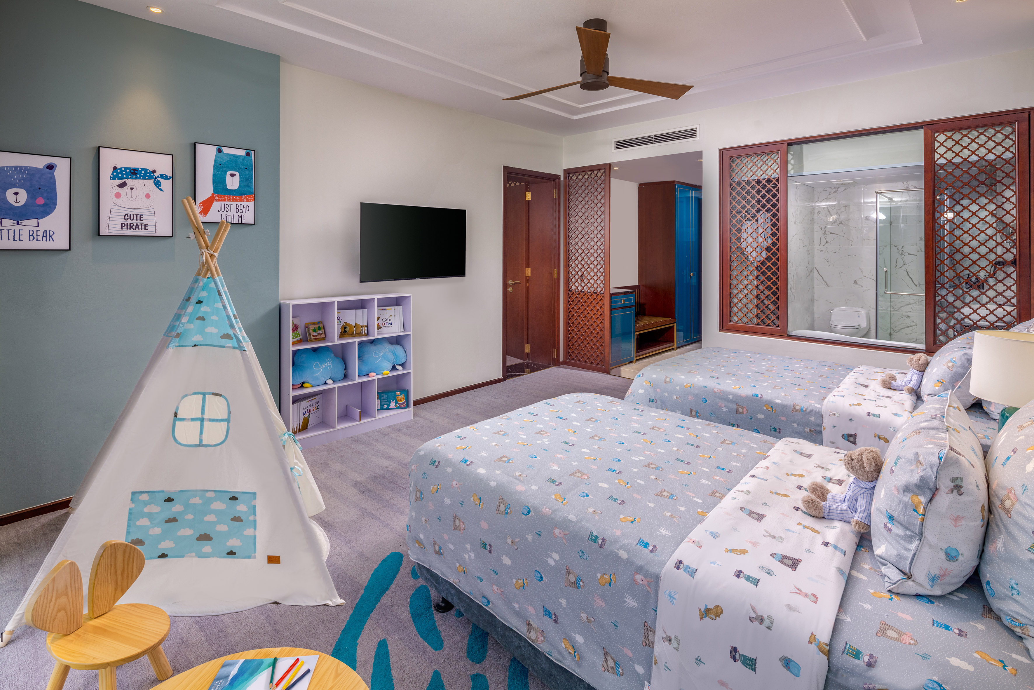 Playful kids' hotel room with twin beds, bear artwork, and a teepee tent.