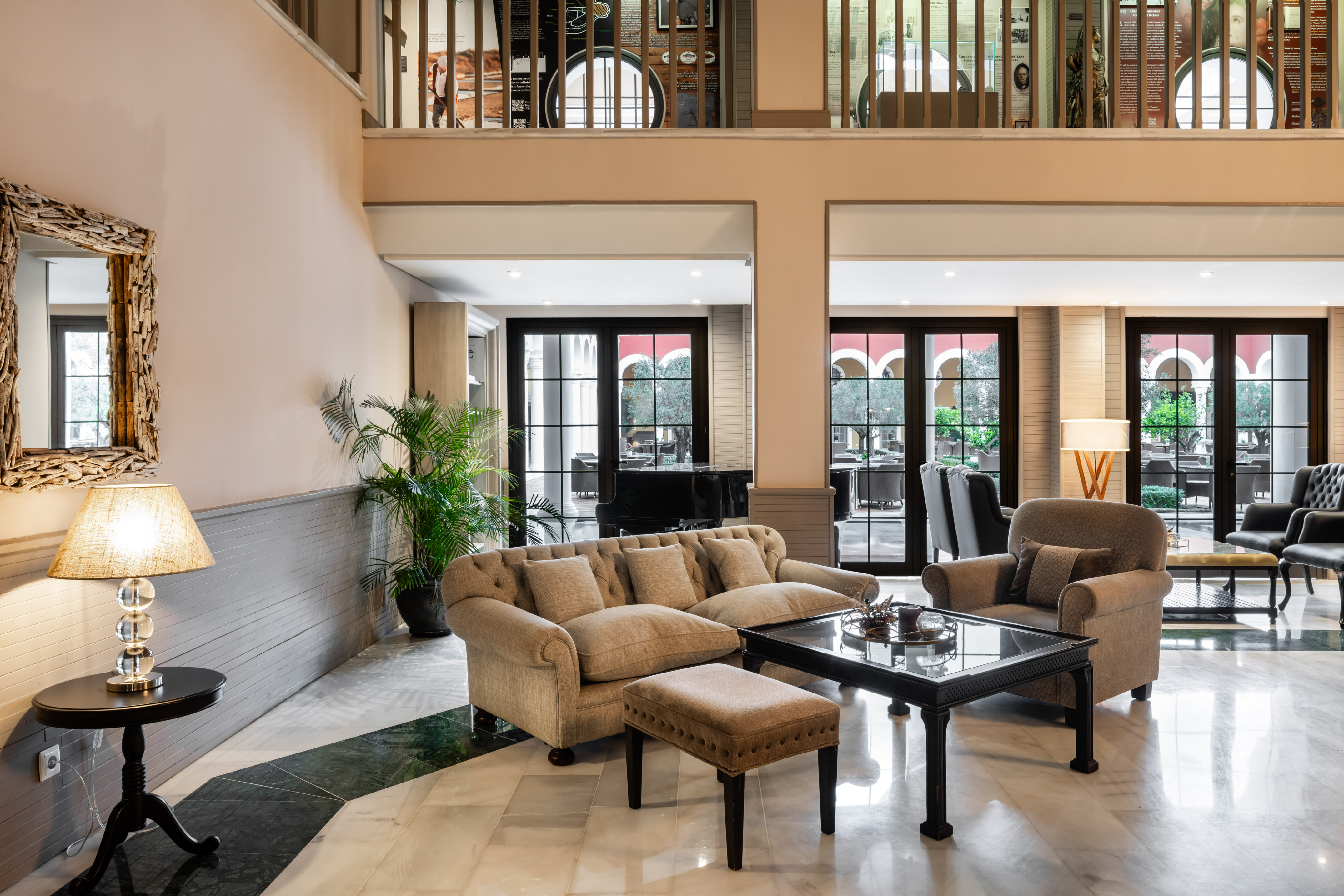 Elegant hotel lounge with comfortable beige seating, marble floor, and garden view.