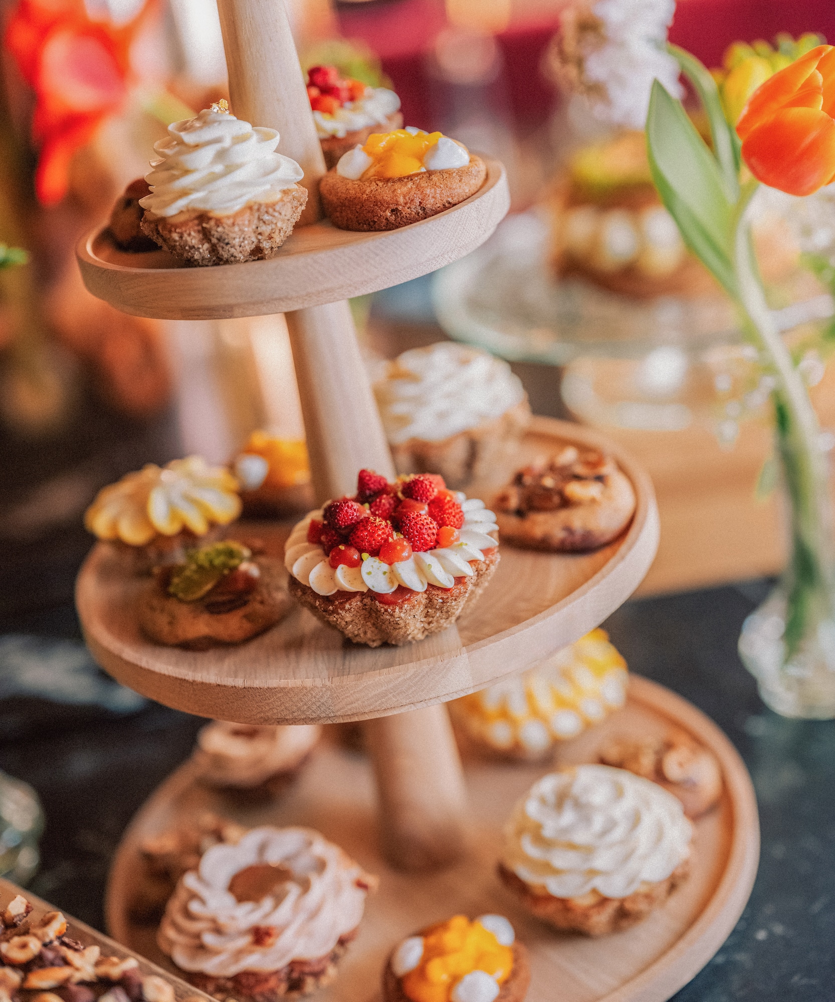 Assorted mini tarts and pastries on a three-tier wooden dessert stand.
