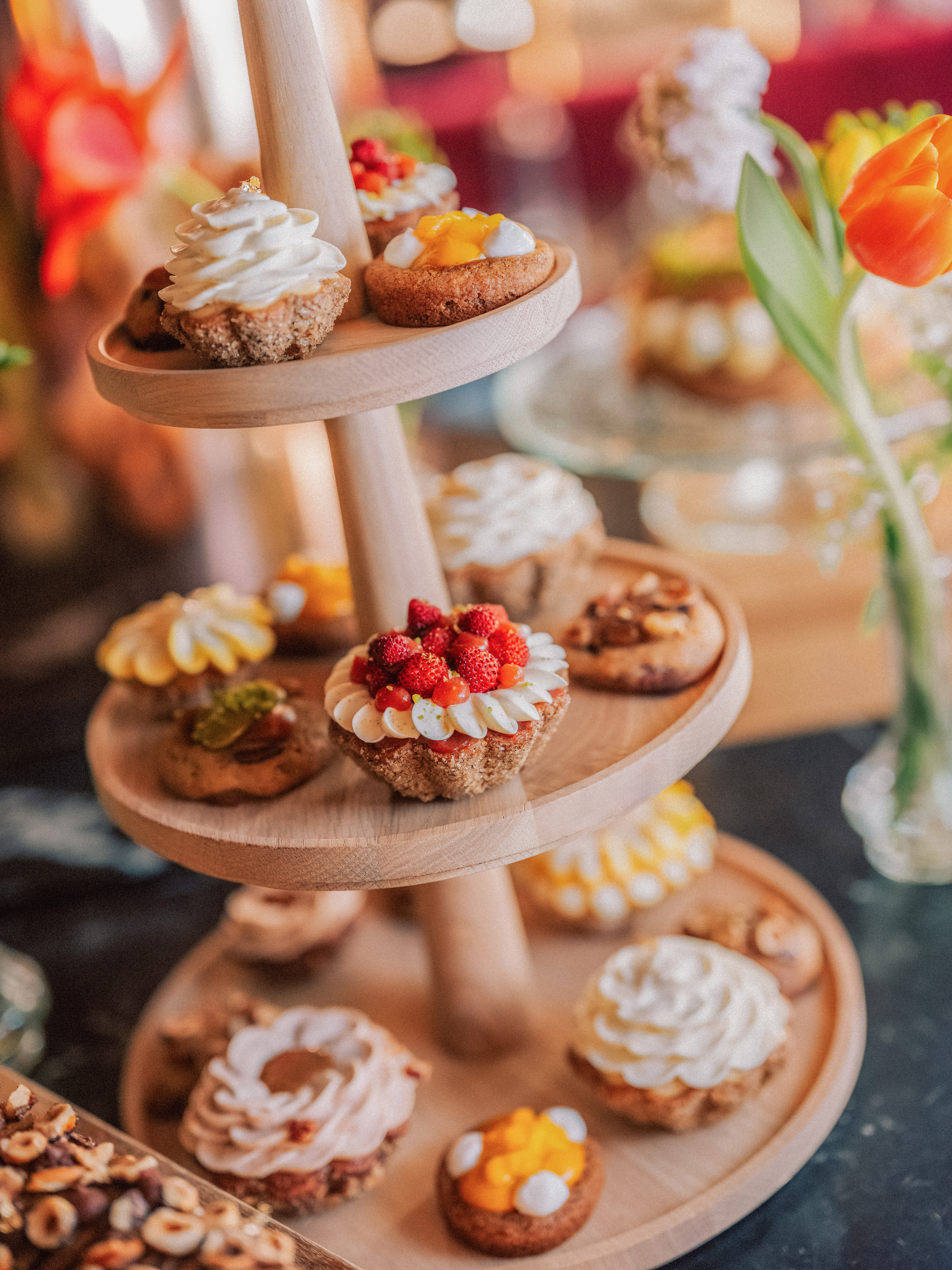 Assorted mini tarts and pastries on a three-tier wooden dessert stand.