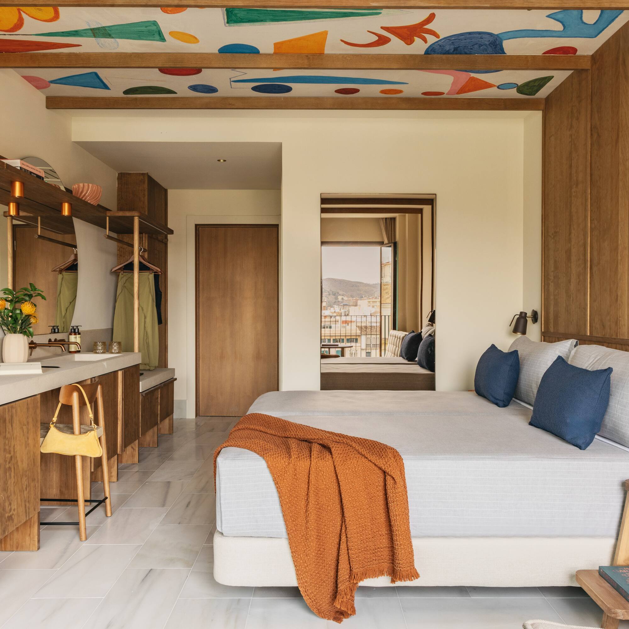 Modern hotel room with abstract ceiling art, wood accents, and balcony view.