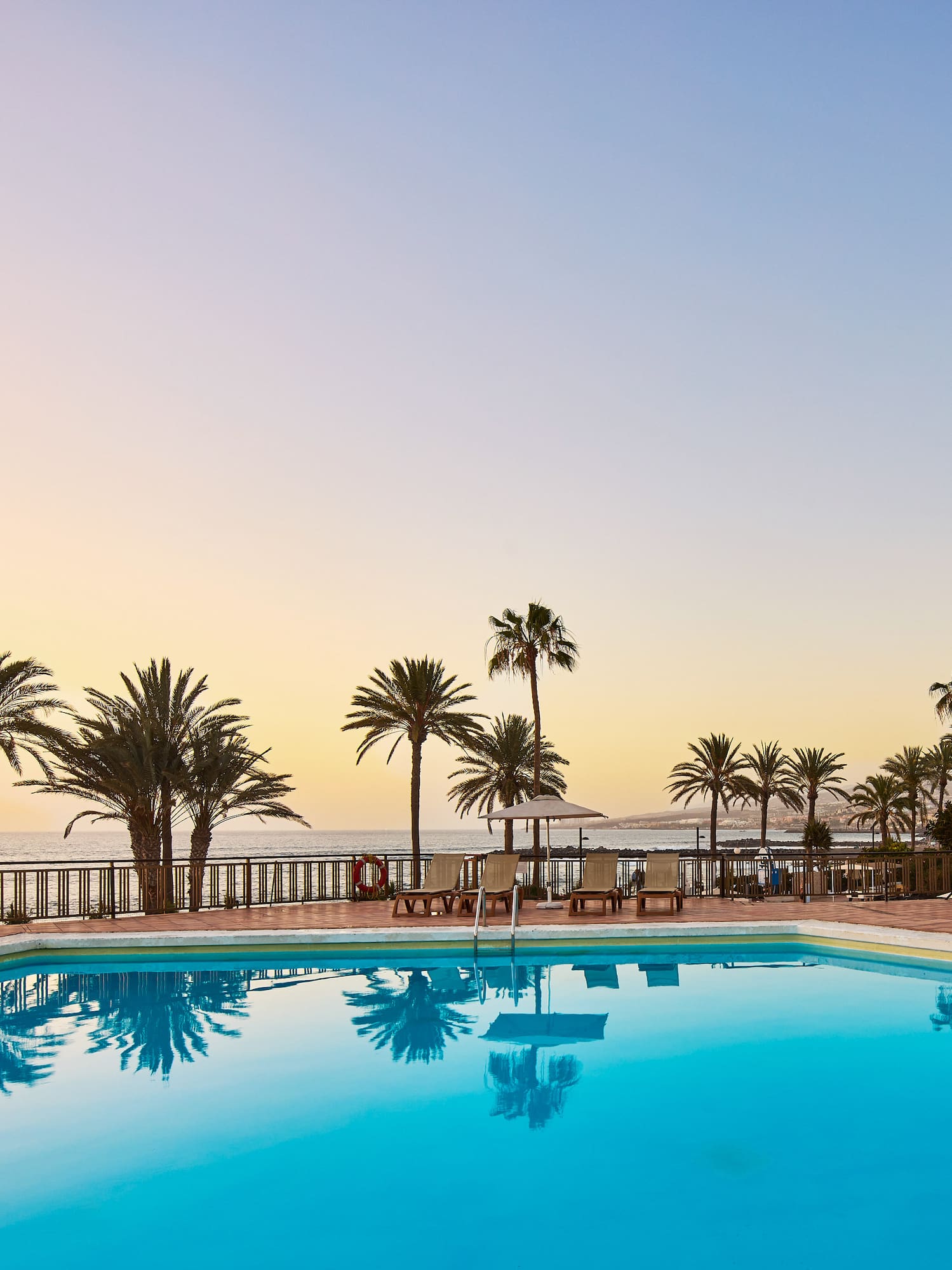 a pool with palm trees and a deck chair