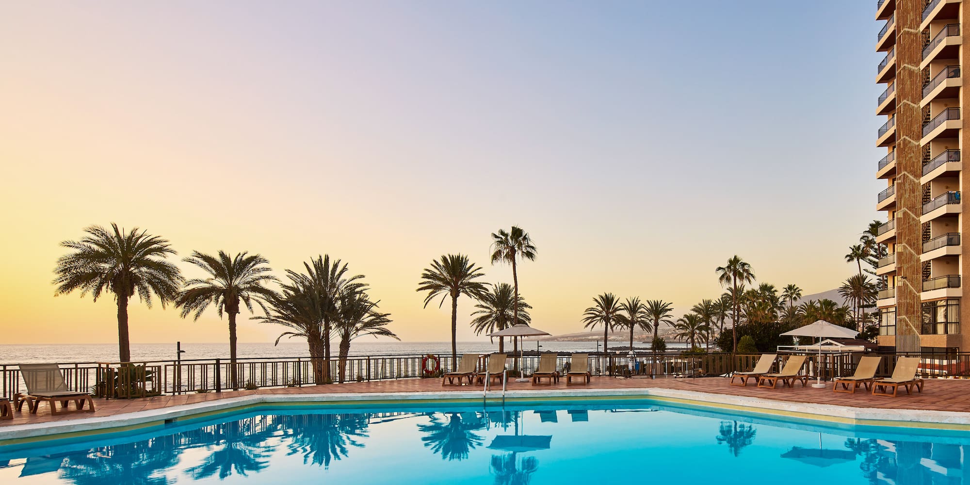 a pool with palm trees and a deck chair