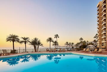 a pool with palm trees and a deck chair