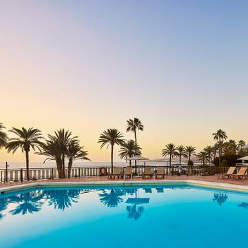 a pool with palm trees and a deck chair