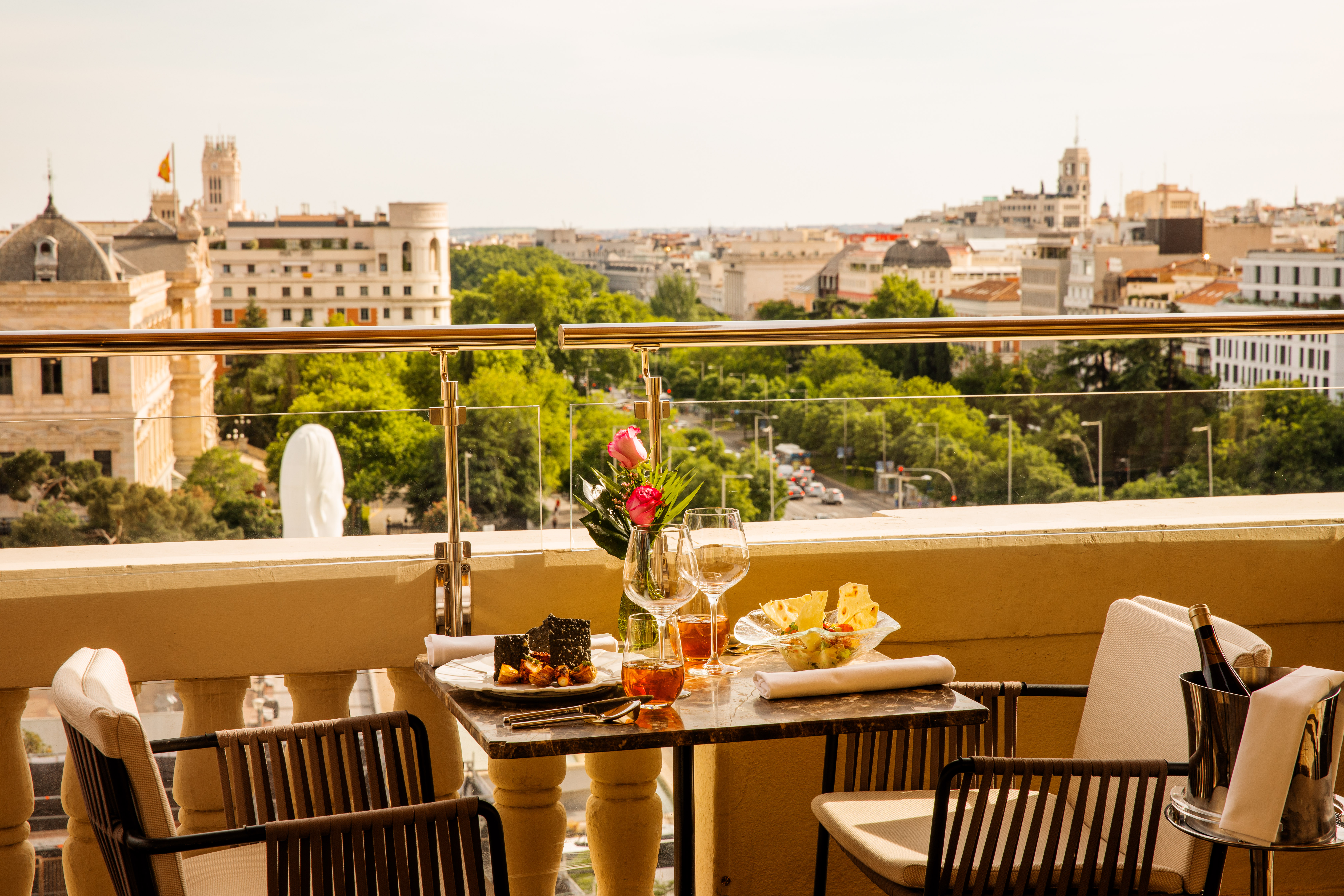 Balcony dining with dessert, wine, and a panoramic Madrid city skyline view.