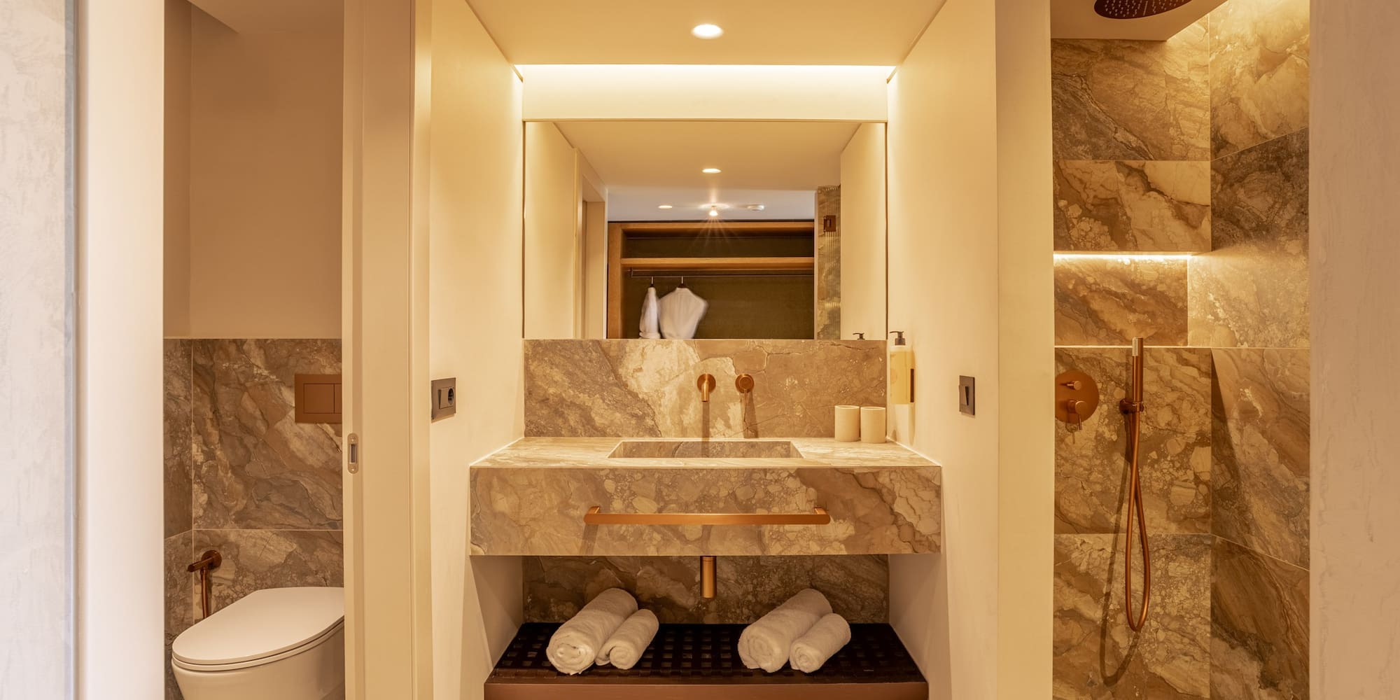 Modern bathroom with marble vanity, copper fixtures, and a walk-in shower.