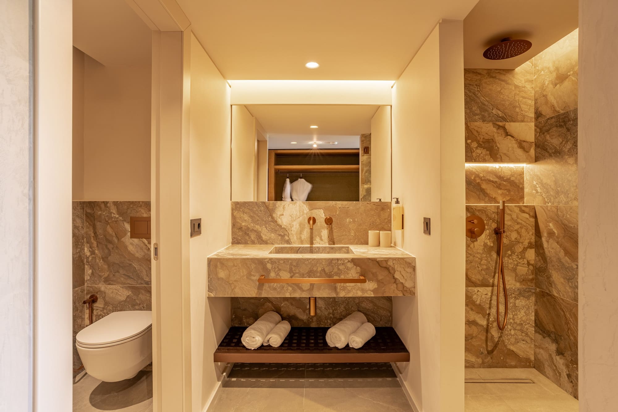 Modern bathroom with marble vanity, copper fixtures, and a walk-in shower.
