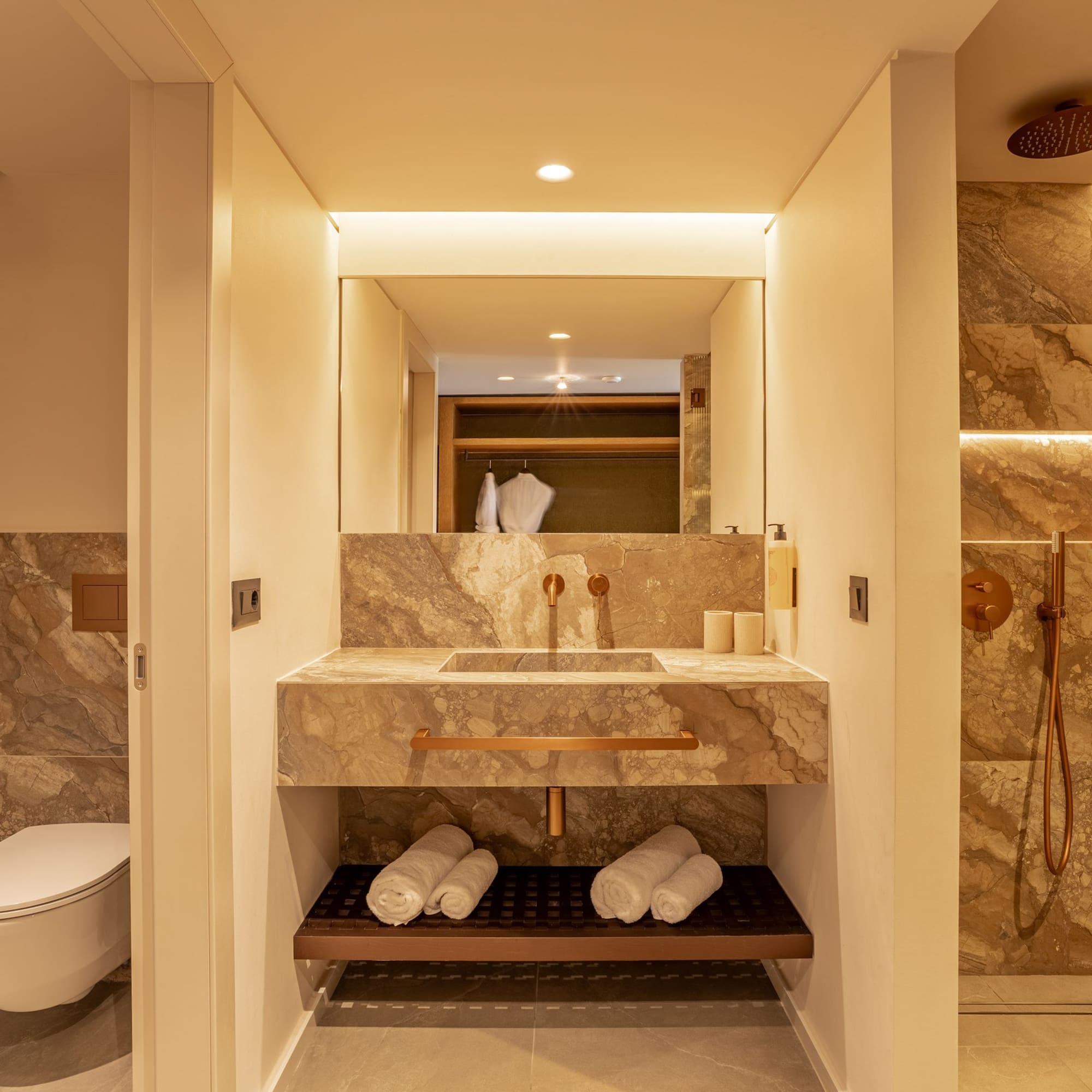 Modern bathroom with marble vanity, copper fixtures, and a walk-in shower.