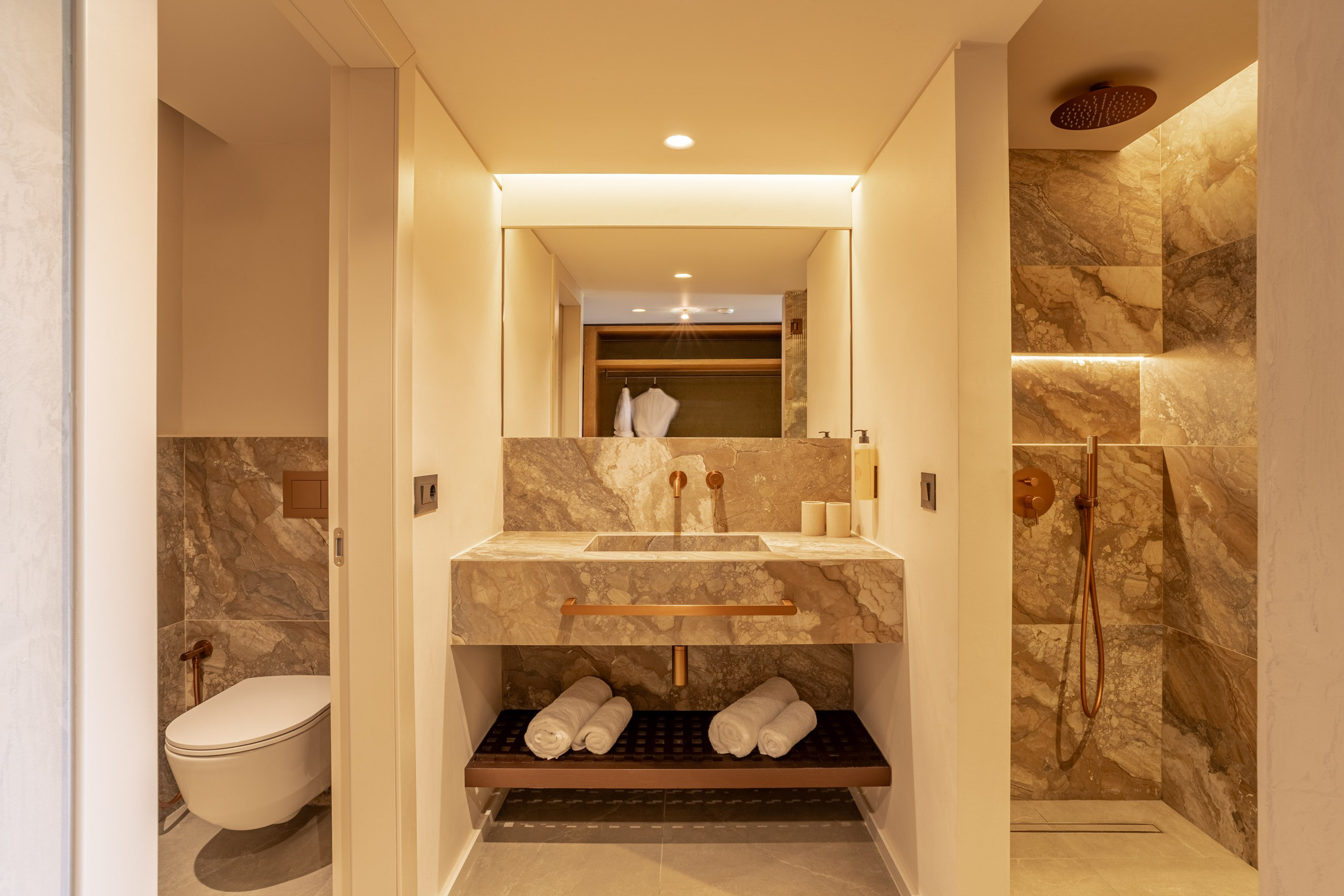 Modern bathroom with marble vanity, copper fixtures, and a walk-in shower.