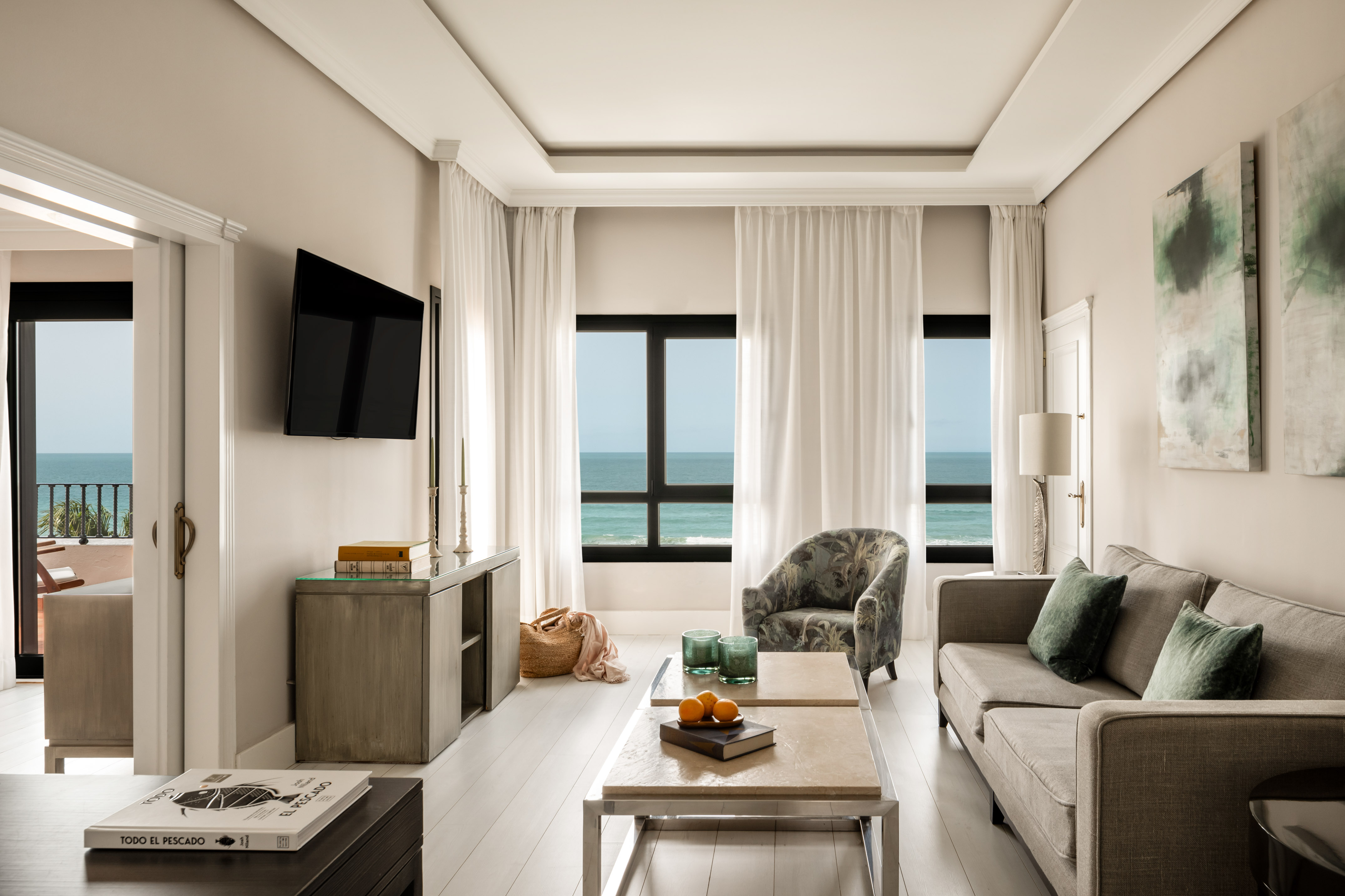 Modern luxury living room with ocean view and balcony.