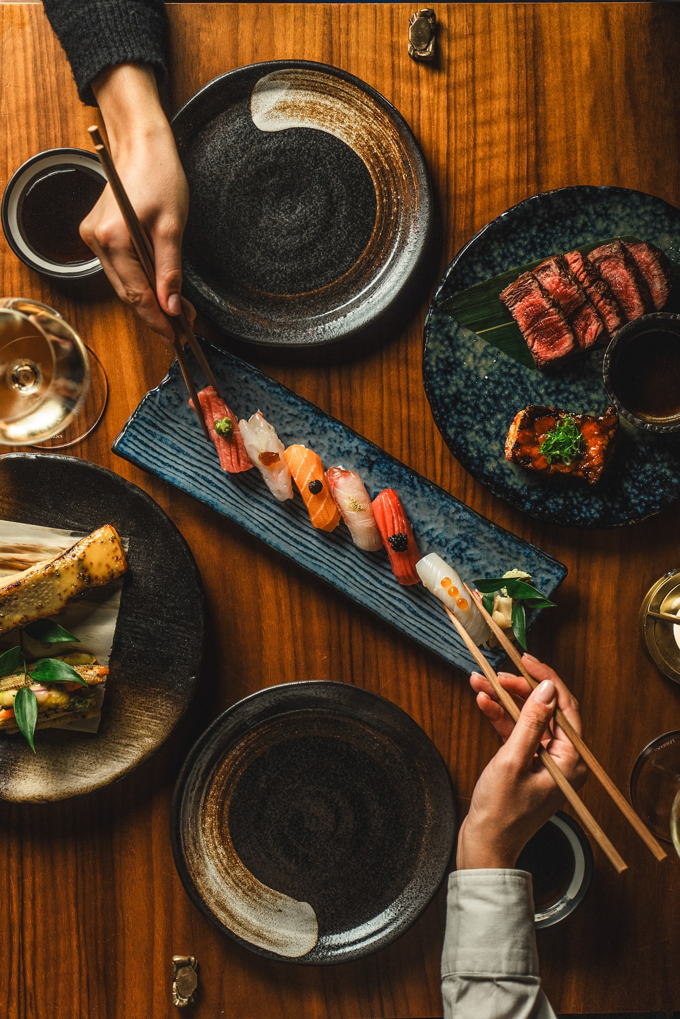 a person holding chopsticks over a plate of sushi