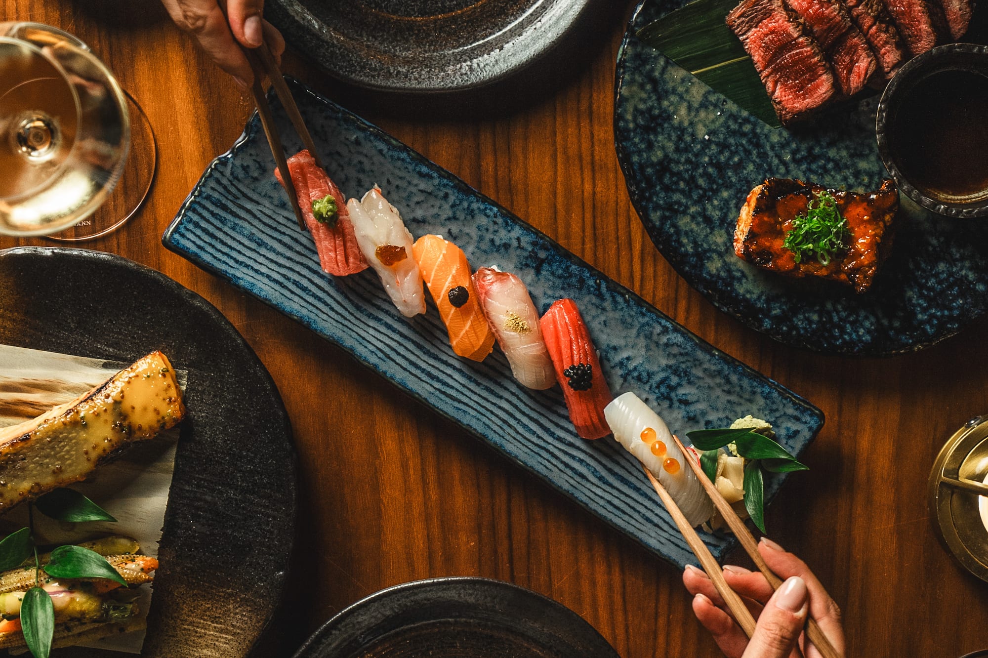 a person holding chopsticks over a plate of sushi