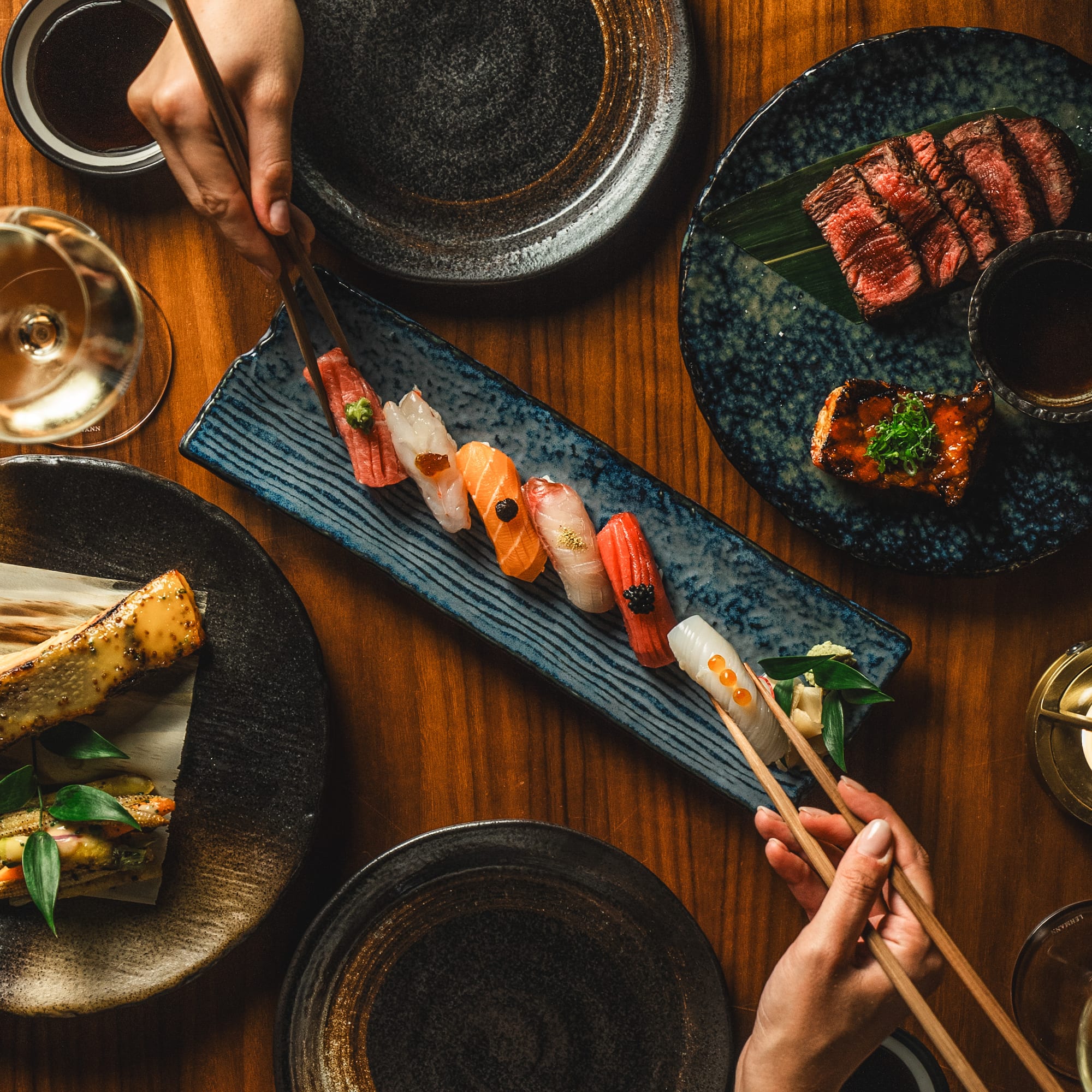 a person holding chopsticks over a plate of sushi