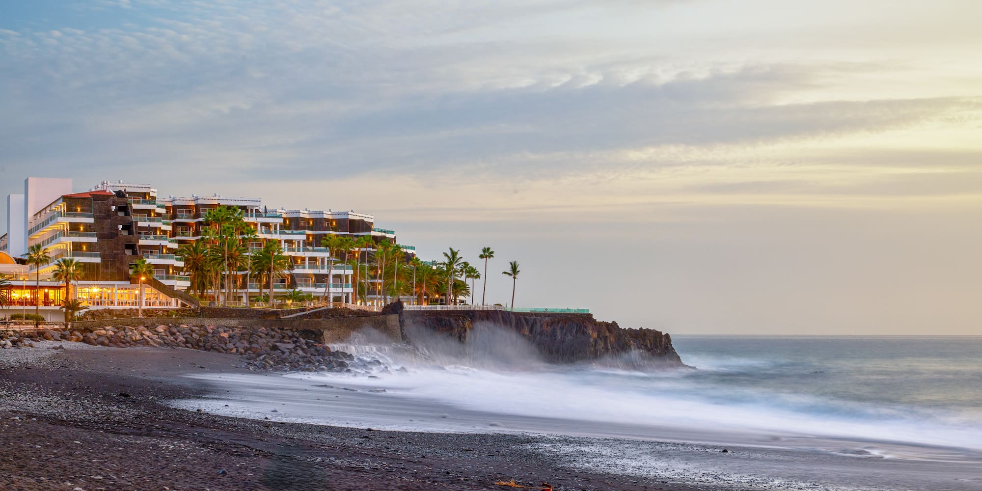 a beach with a building and palm trees