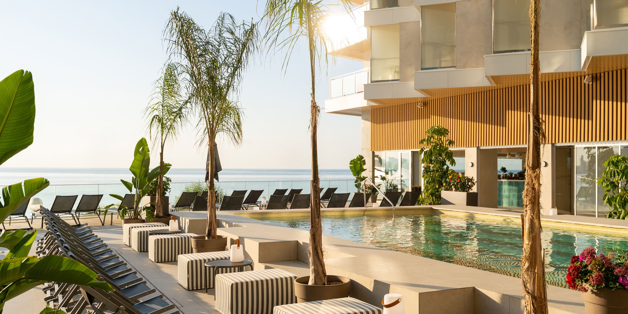 a pool with lounge chairs and palm trees by a building