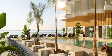 a pool with lounge chairs and palm trees by a building