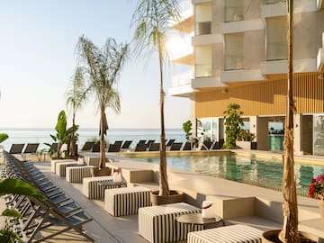 a pool with lounge chairs and palm trees by a building
