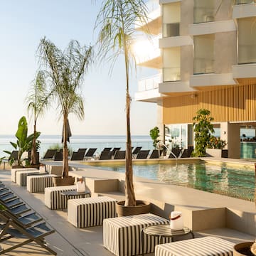 a pool with lounge chairs and palm trees by a building