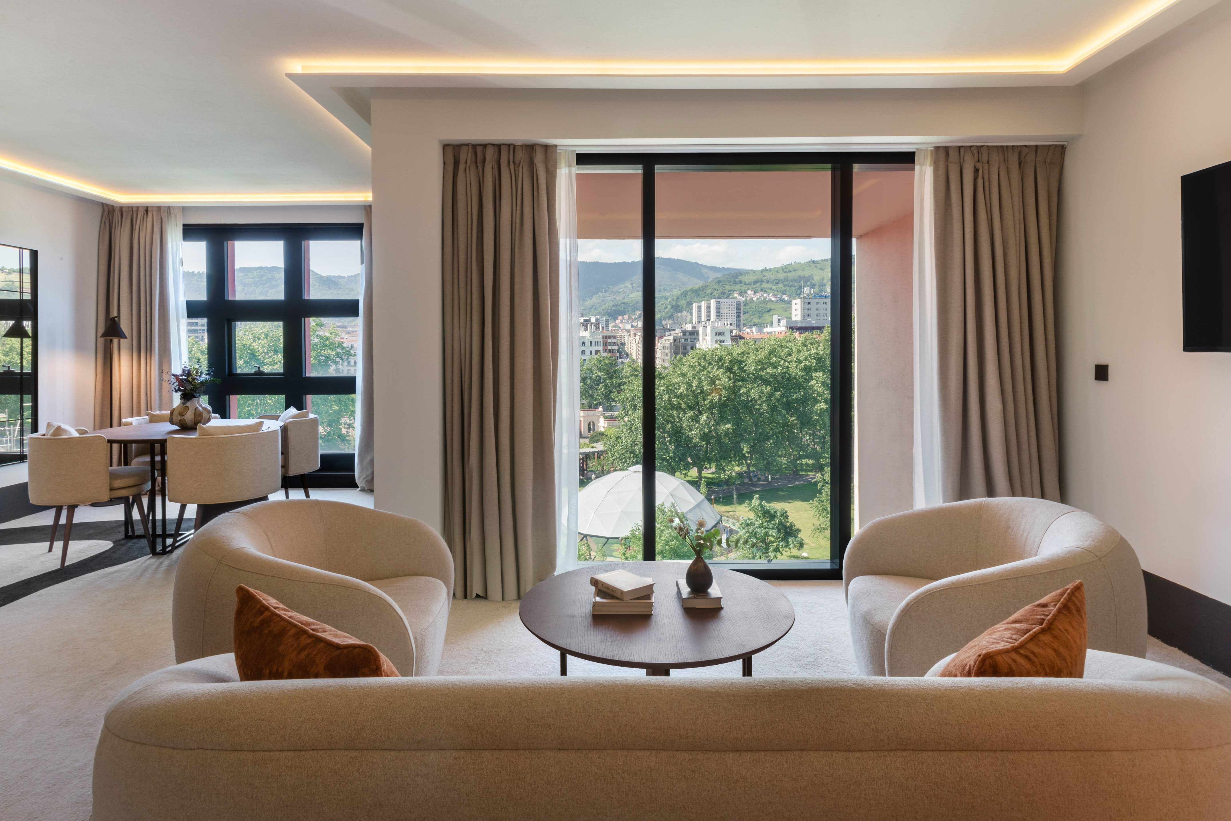 Stylish living room with panoramic city and mountain views, neutral decor.