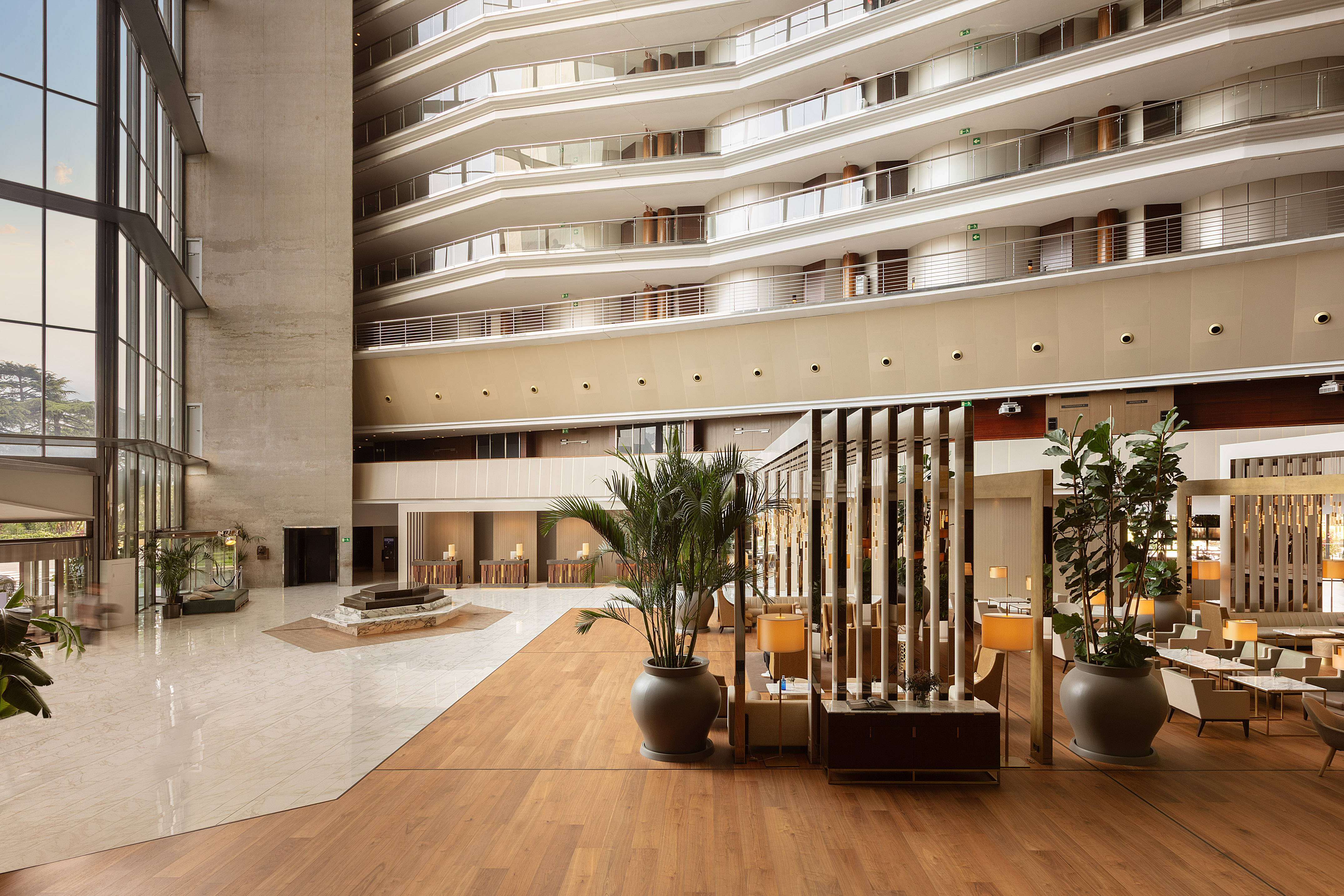 Spacious modern hotel lobby with multi-story atrium, large windows, and seating.