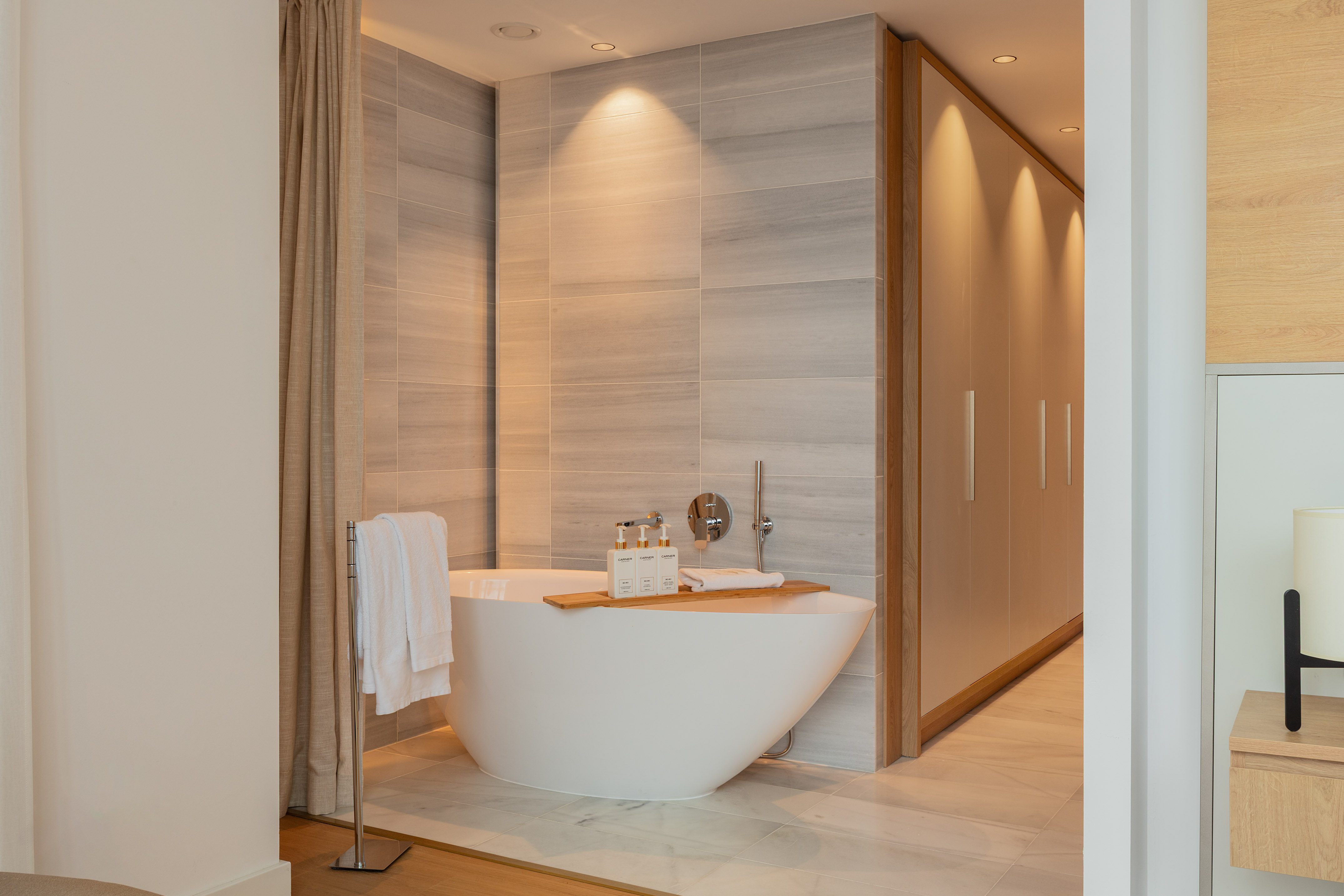 Modern luxury bathroom with freestanding tub, tiled wall, and built-in storage.