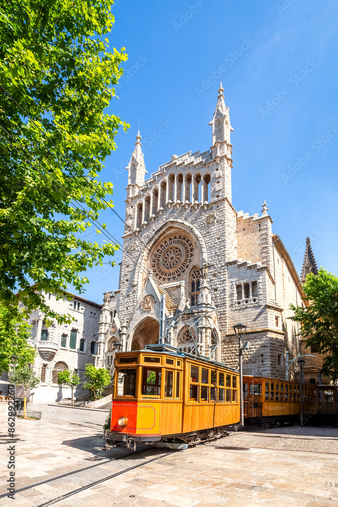 Vintage wooden tram by ornate Gothic church with rose window.