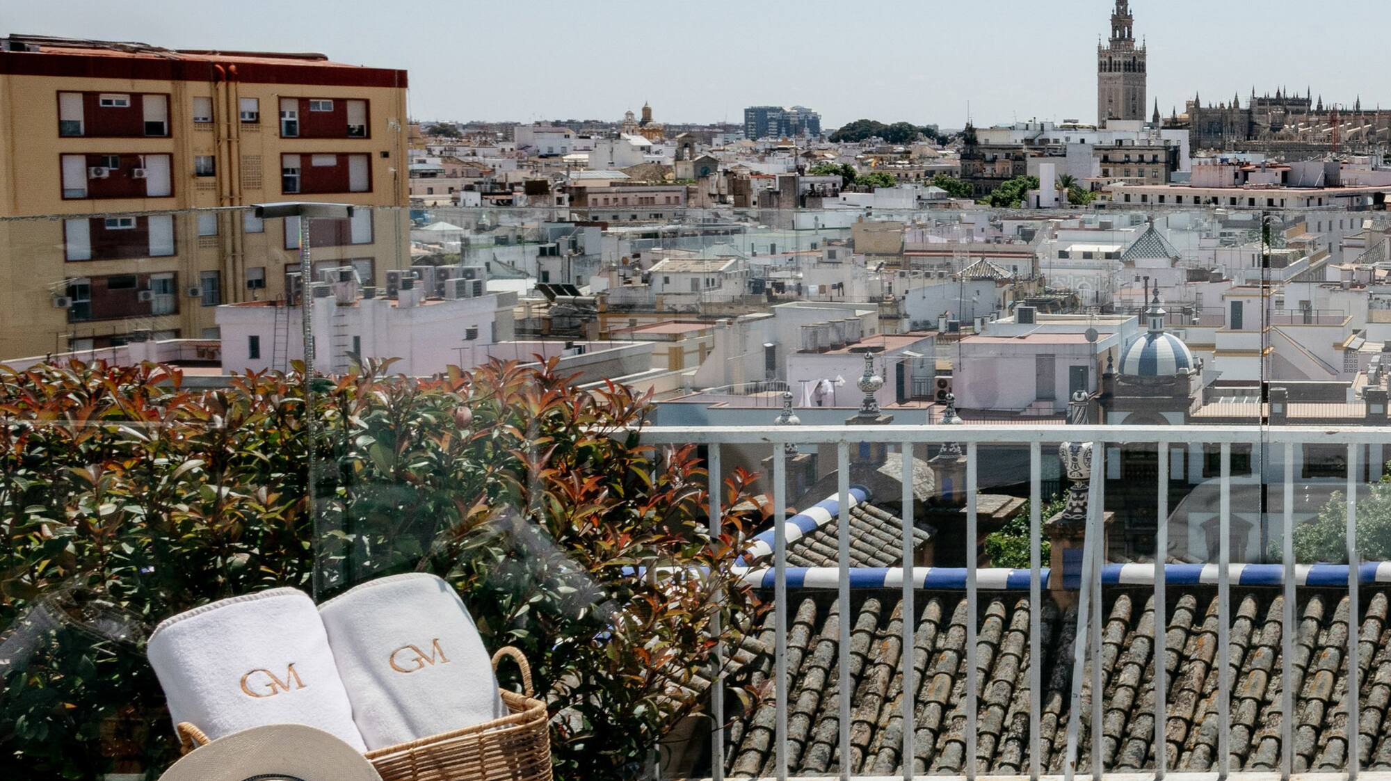 a basket with towels and a hat on a balcony overlooking a city