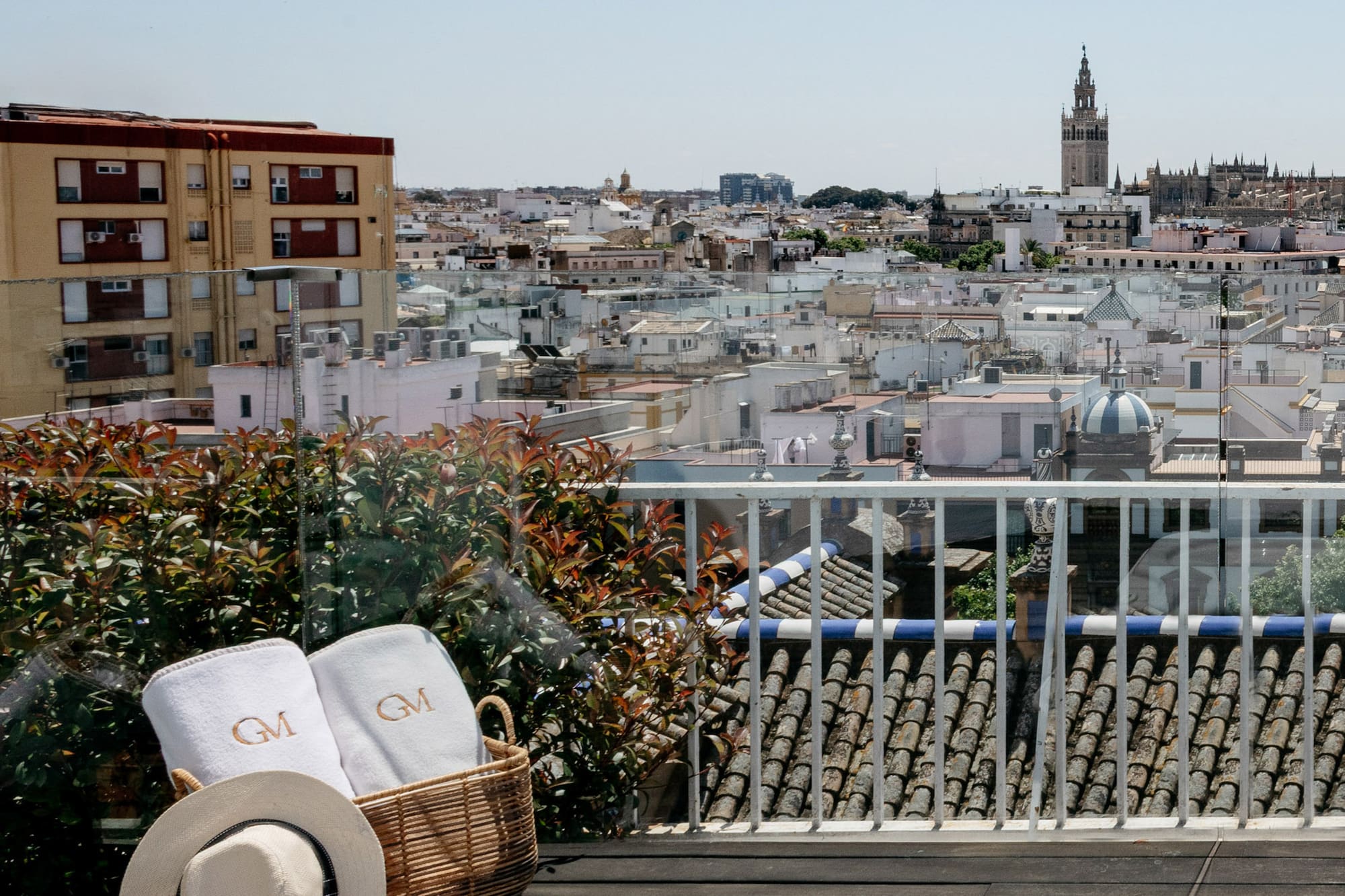 a basket with towels and a hat on a balcony overlooking a city