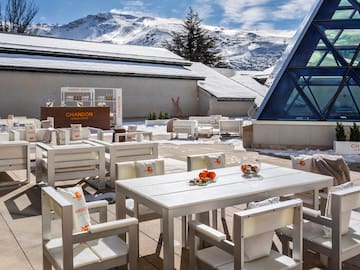 a white tables and chairs outside with snow covered mountains in the background