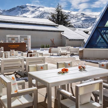 a white tables and chairs outside with snow covered mountains in the background