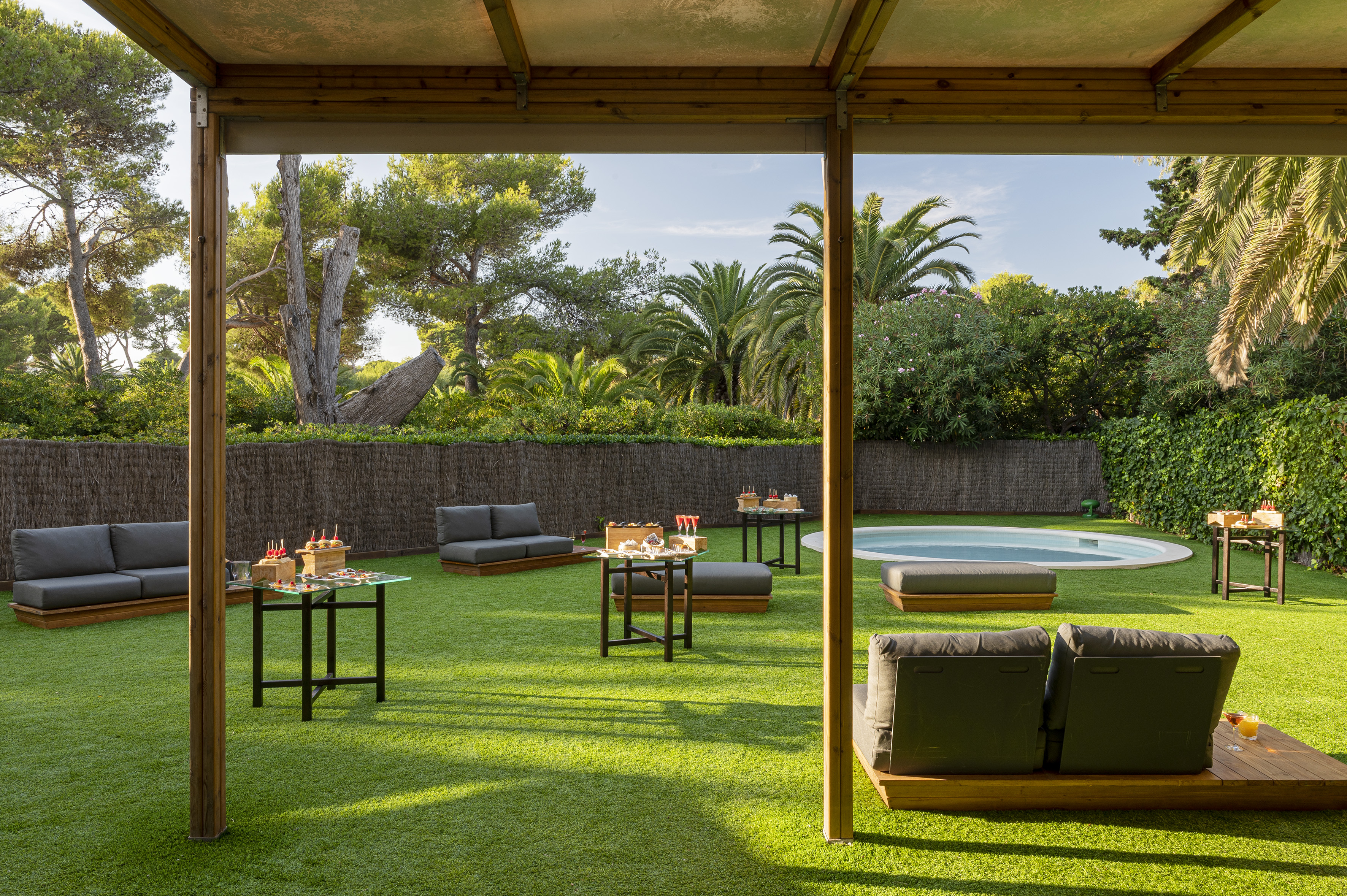 Outdoor garden lounge with artificial grass, small pool, and snack tables.