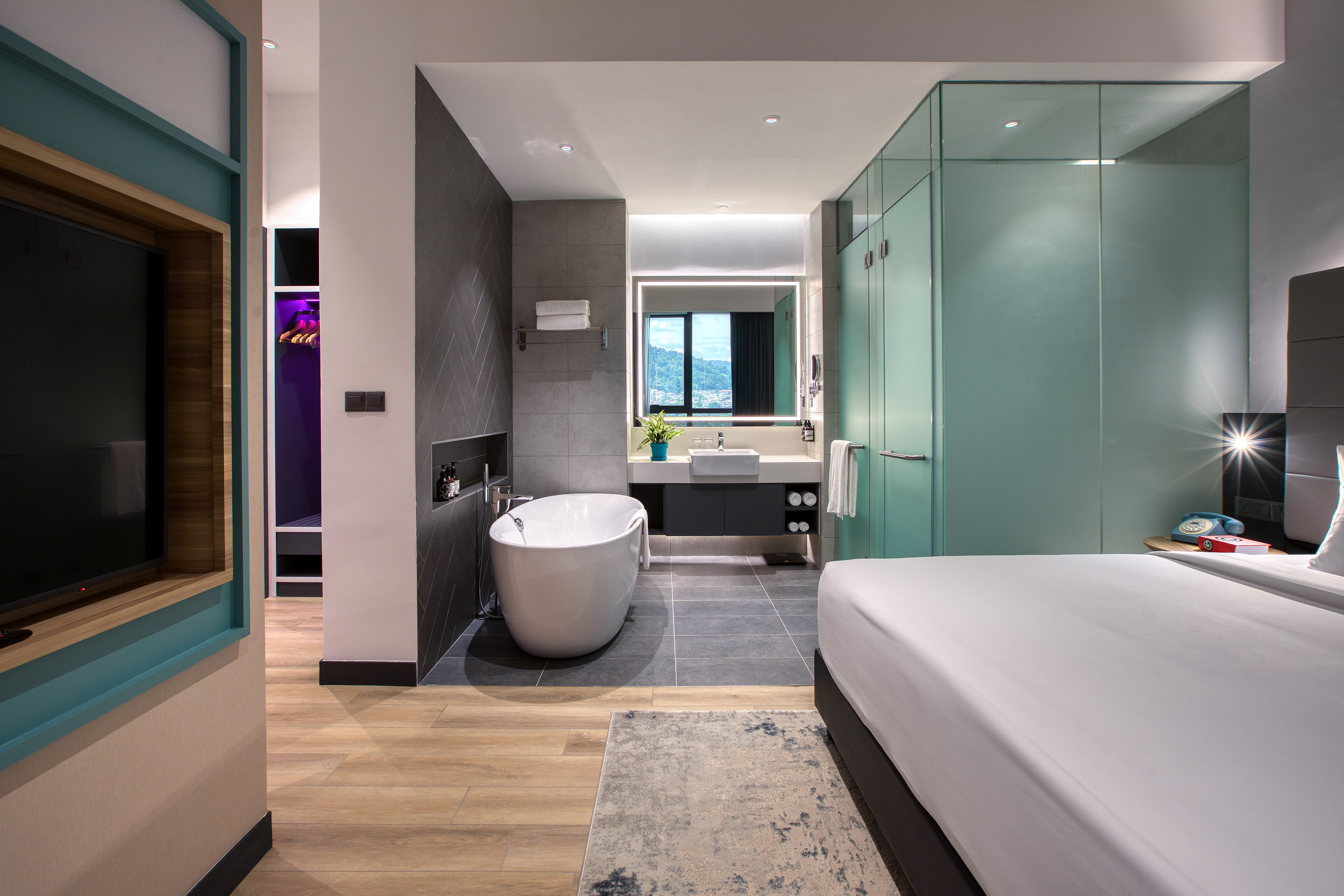 Modern hotel suite with open bathroom, freestanding tub, and bedroom.